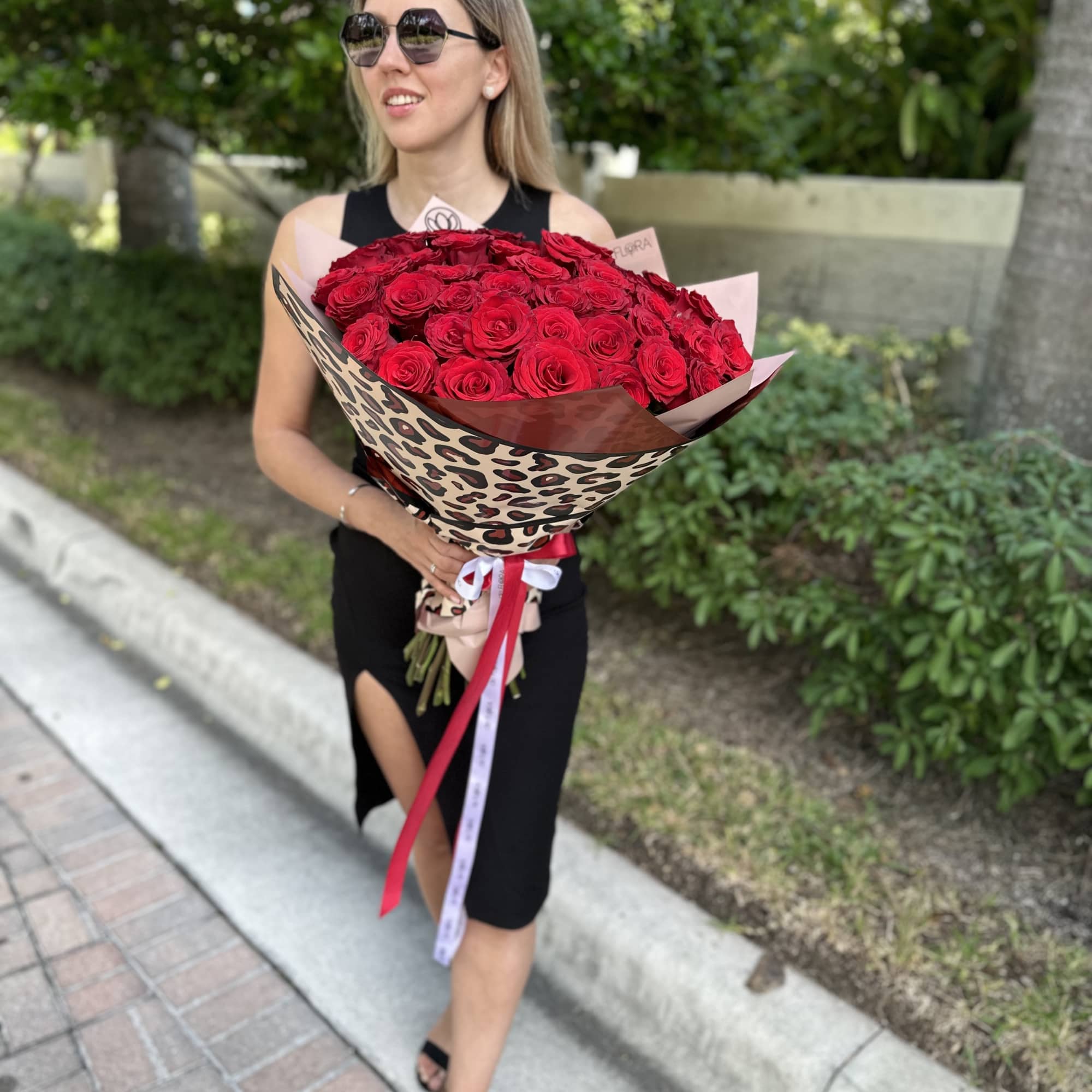 Woman holding a large bouquet of red roses wrapped in patterned paper