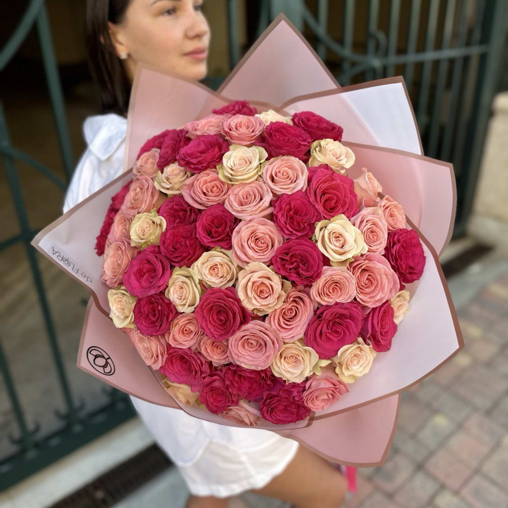 Large bouquet of pink and cream roses wrapped in pink paper