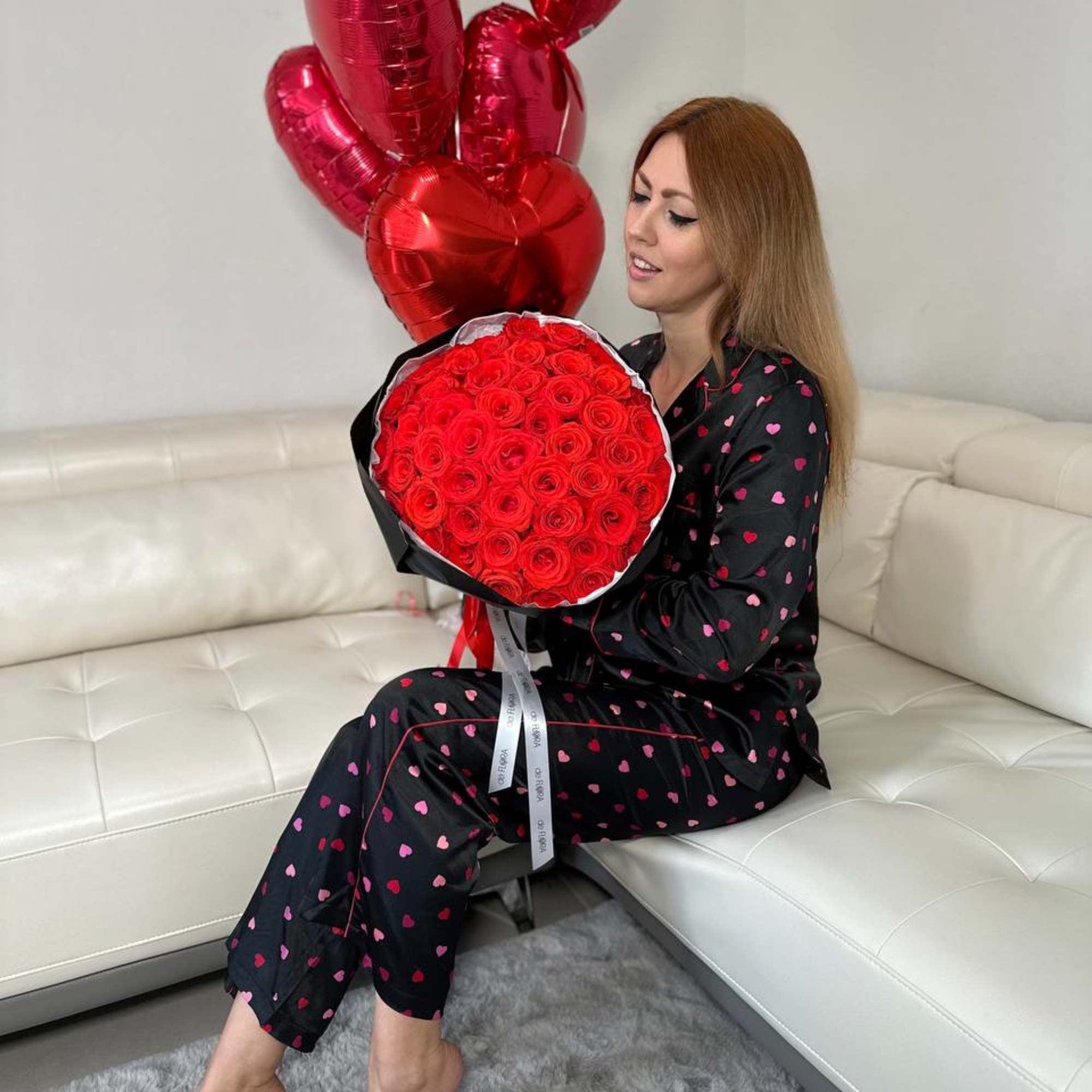 Woman holding a bouquet of red roses with red heart balloons