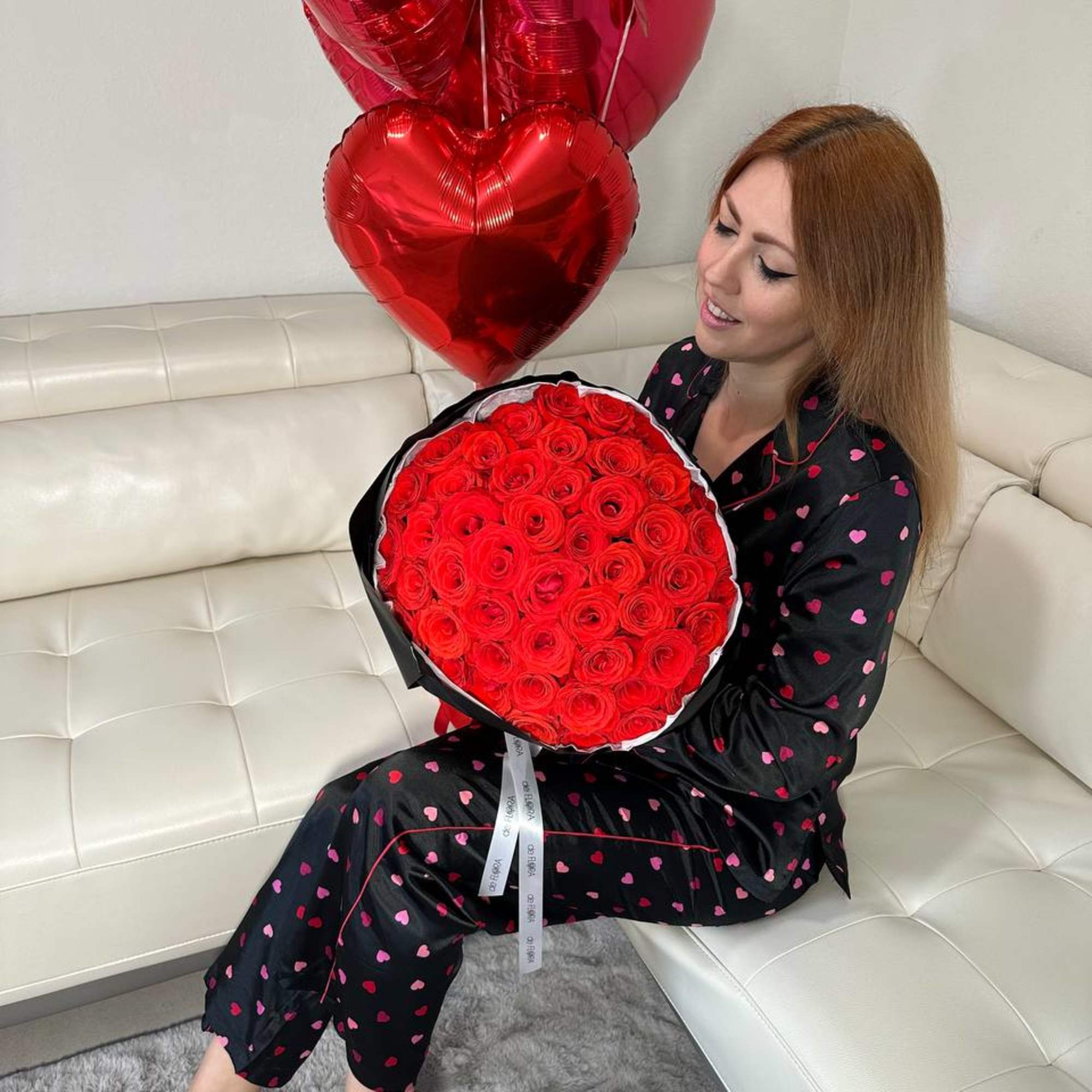 Woman holding a bouquet of red roses with red heart balloons