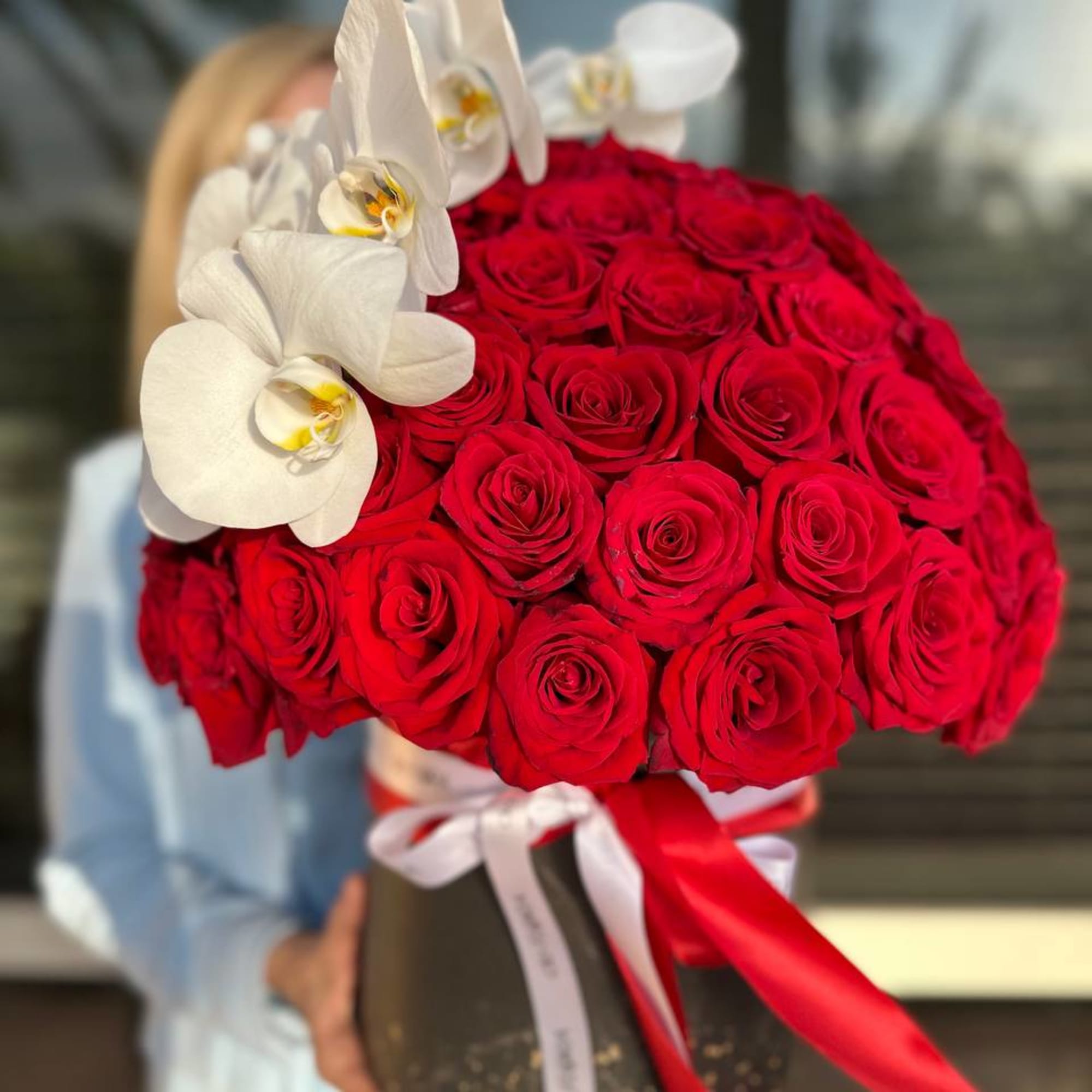 Red rose bouquet with white orchids in a black box tied with ribbons
