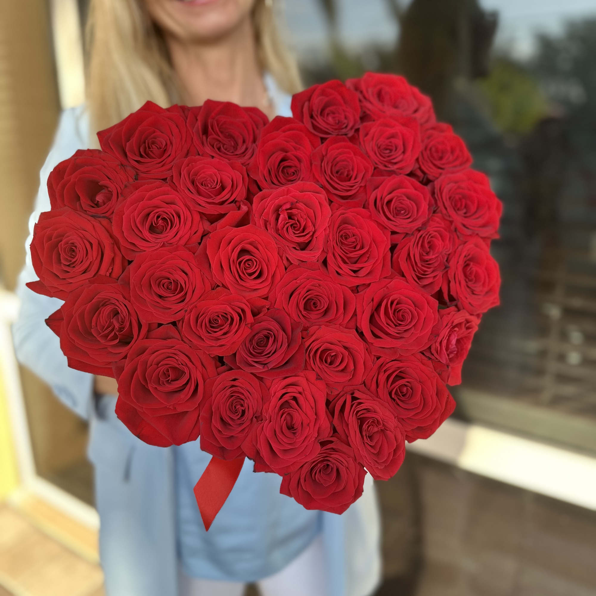 Large bouquet of red roses held by a woman