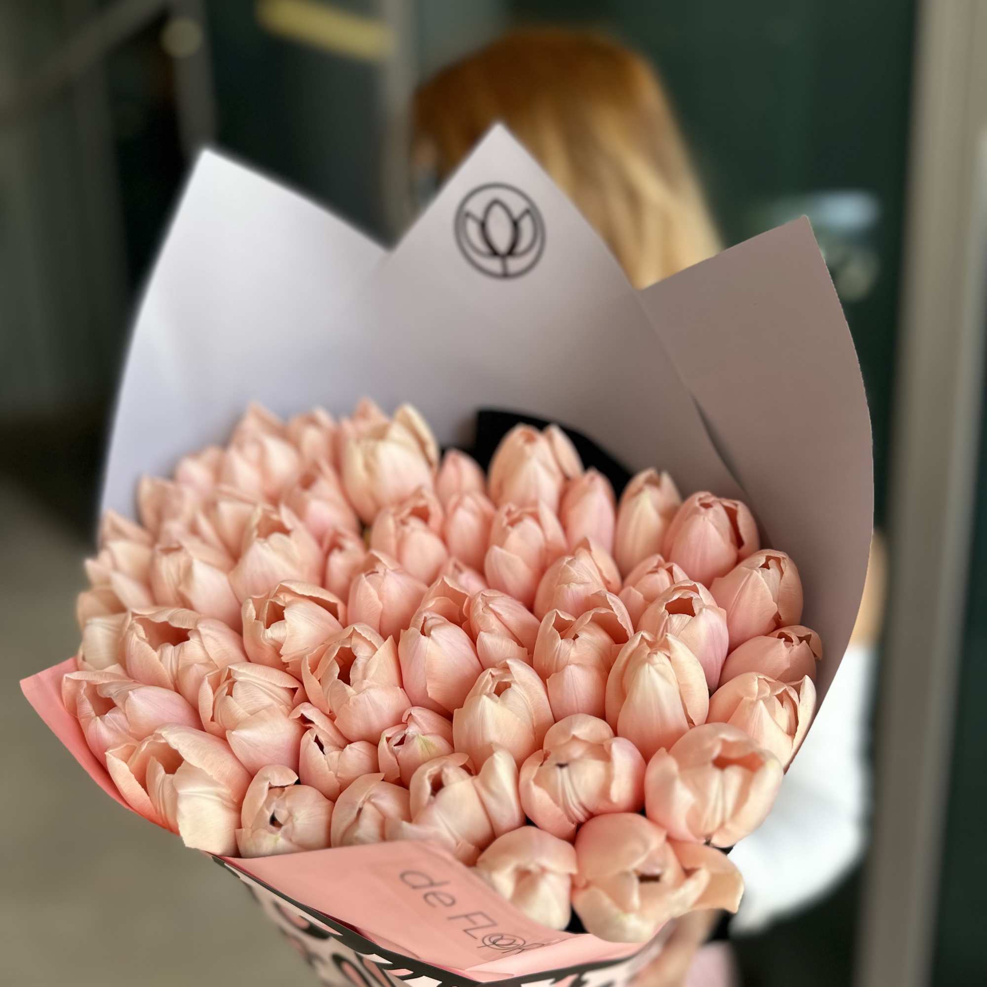Bouquet of pale pink tulips wrapped in pink and white paper