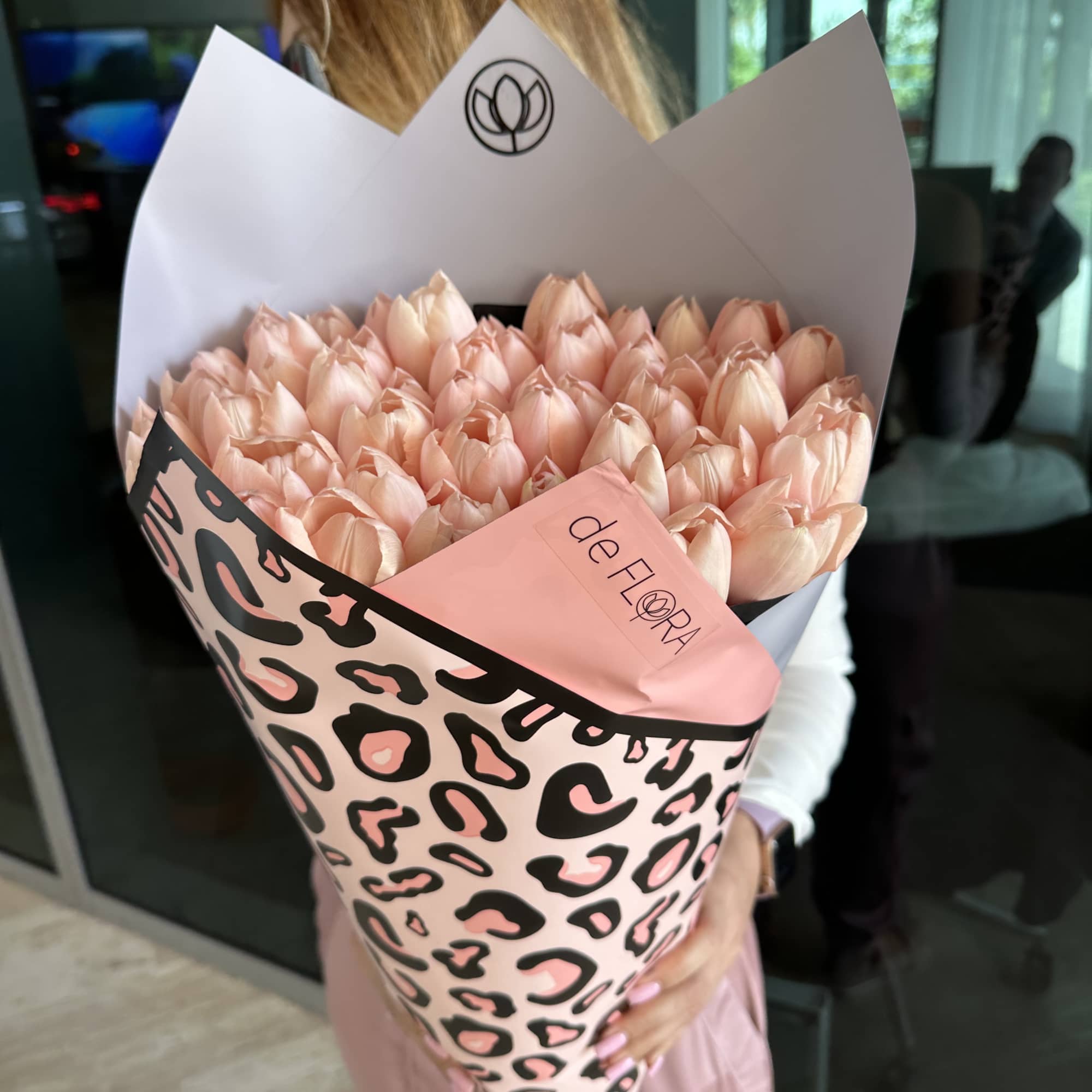 Large bouquet of pale peach tulips wrapped in pink leopard-print paper