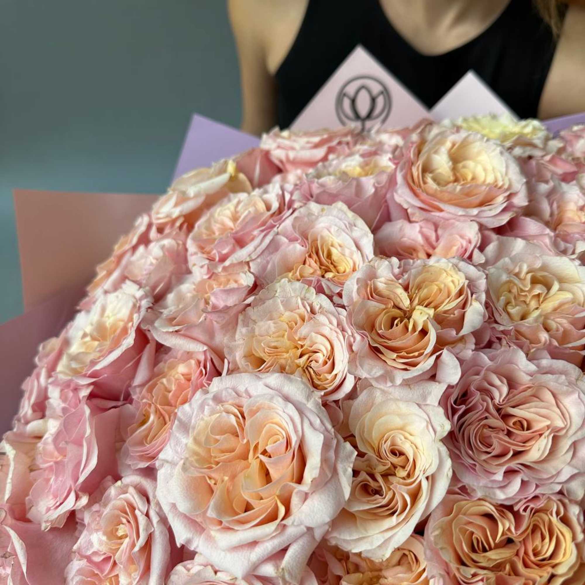Large bouquet of blush and peach roses wrapped in pink paper