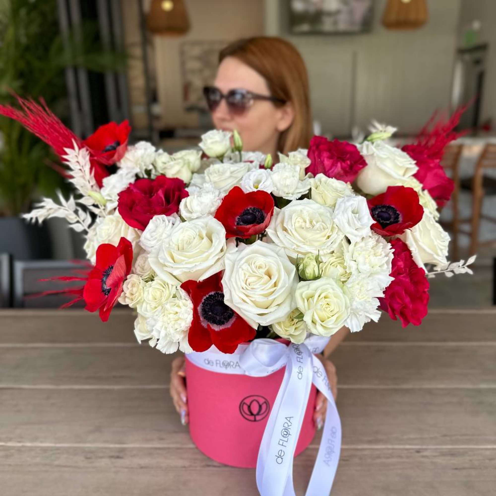 Large bouquet of red and white flowers in a pink hatbox with a ribbon