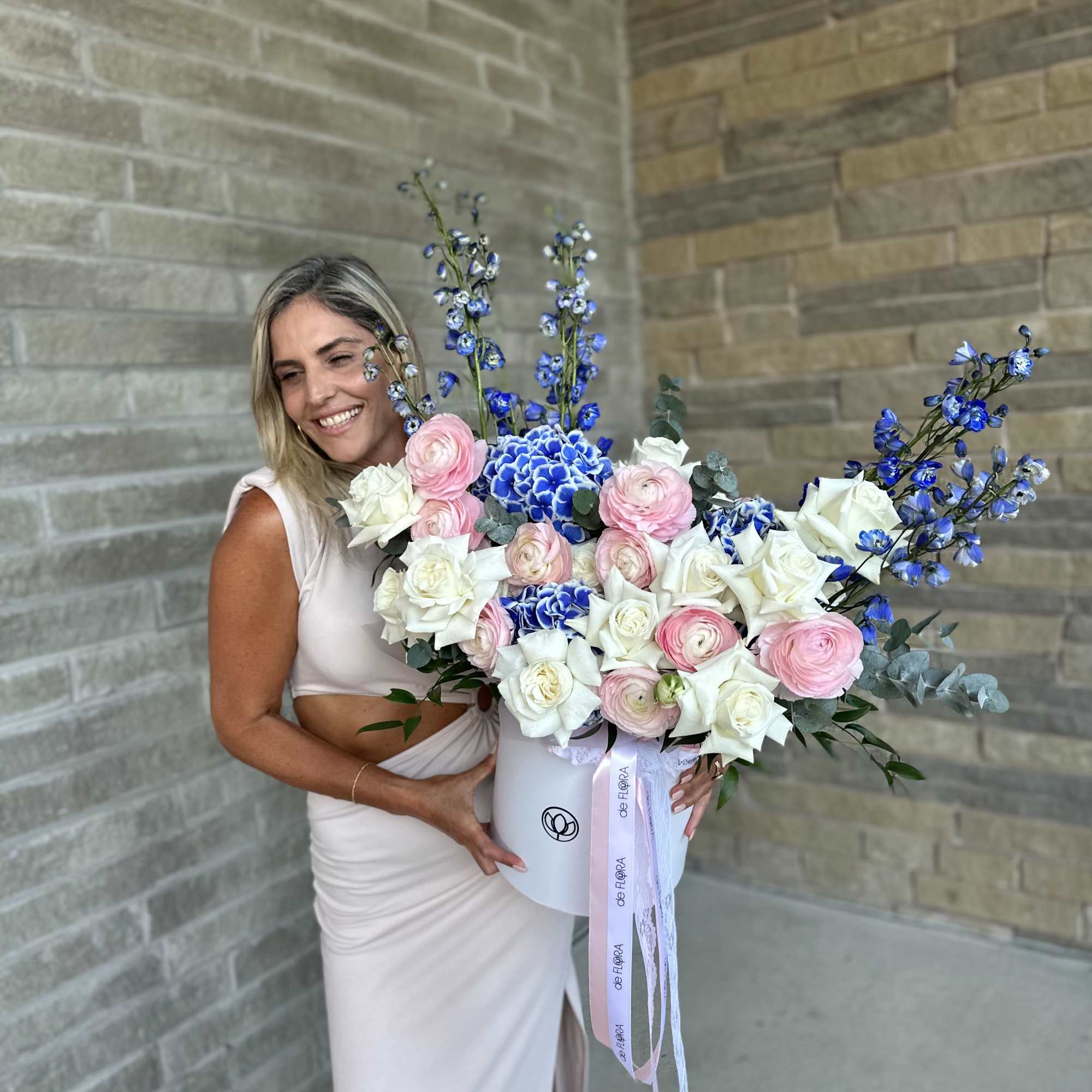 Large bouquet of pink and white roses with blue flowers in a white box