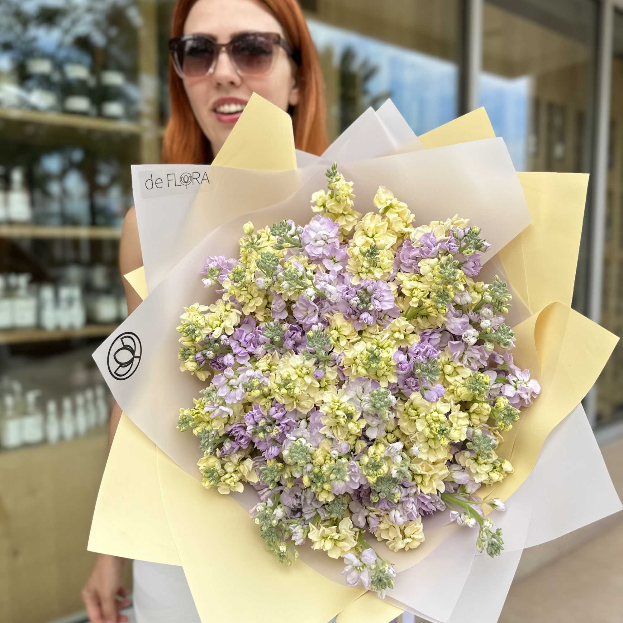Large pastel bouquet of lavender and yellow flowers wrapped in paper