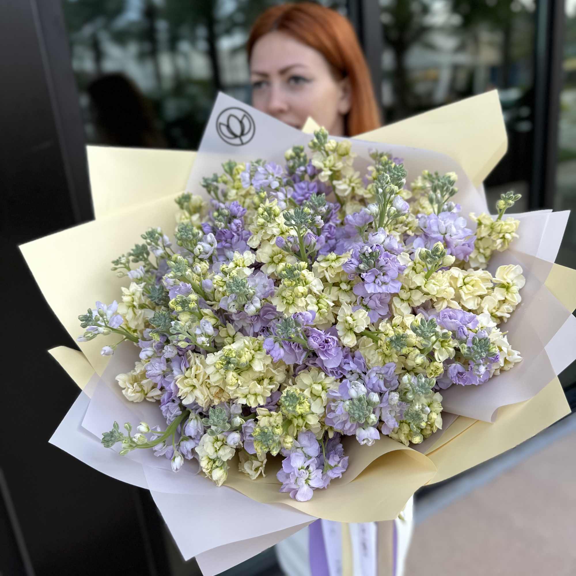 Large bouquet of lavender and cream flowers wrapped in pastel paper