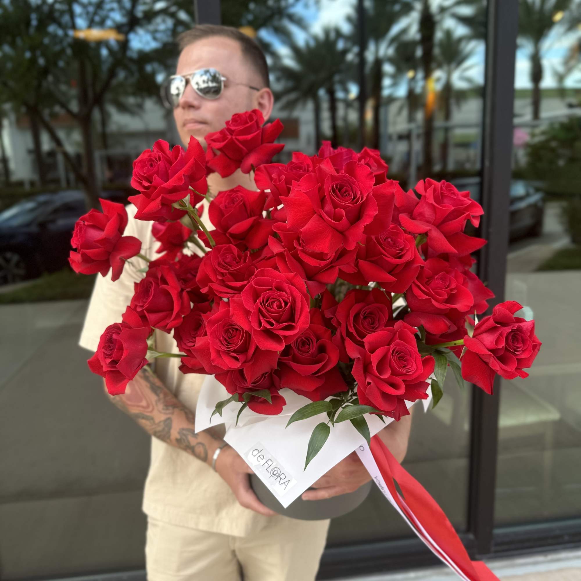 Large bouquet of red roses wrapped in white paper with a red ribbon