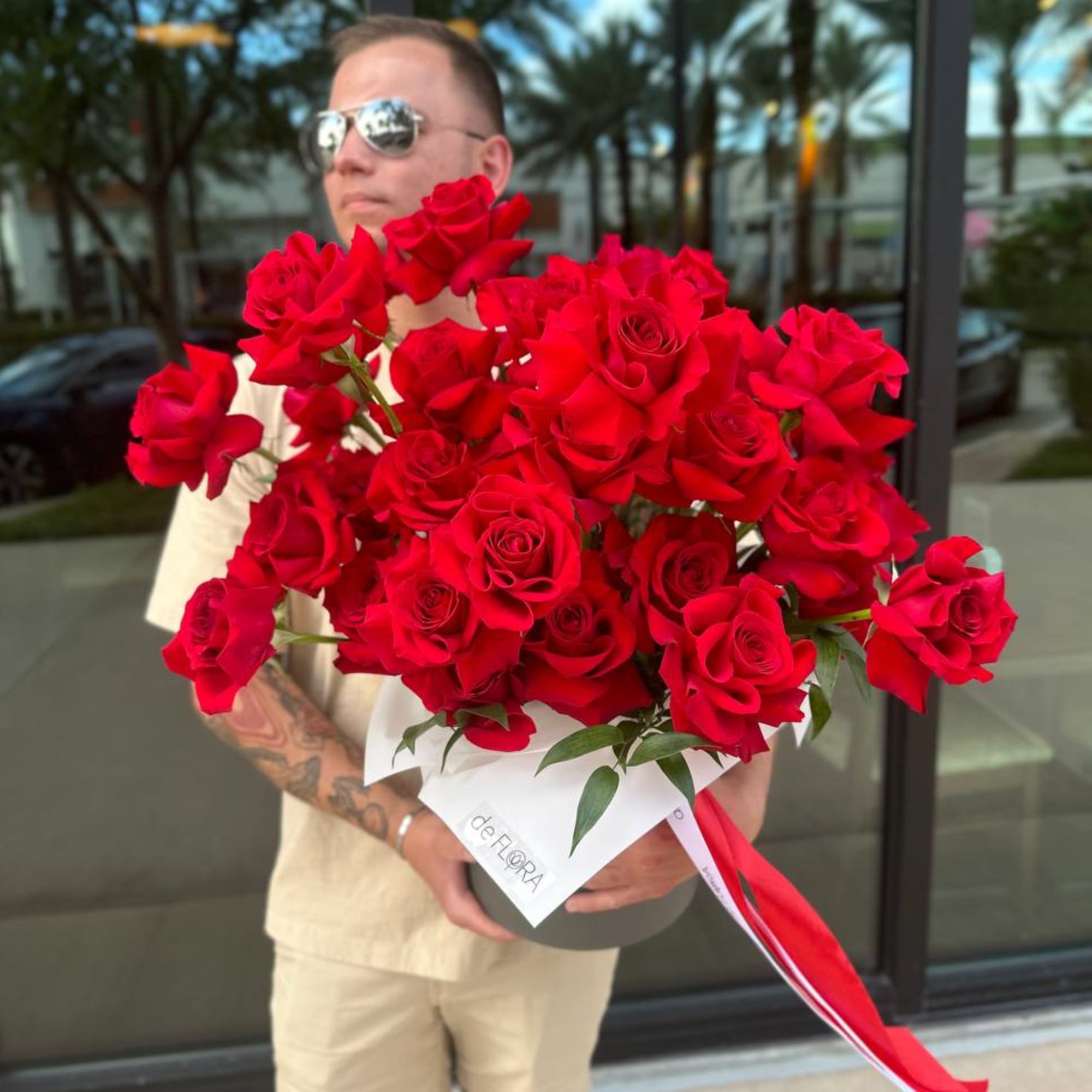 Large bouquet of red roses wrapped in white paper with a red ribbon