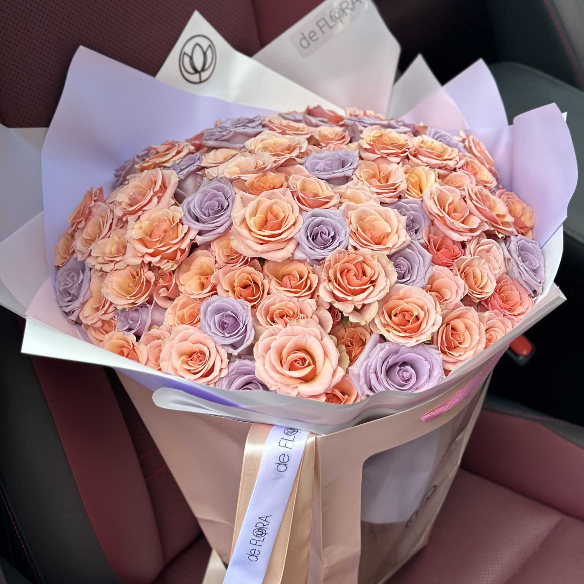 Bouquet of peach and lavender roses wrapped in pastel paper
