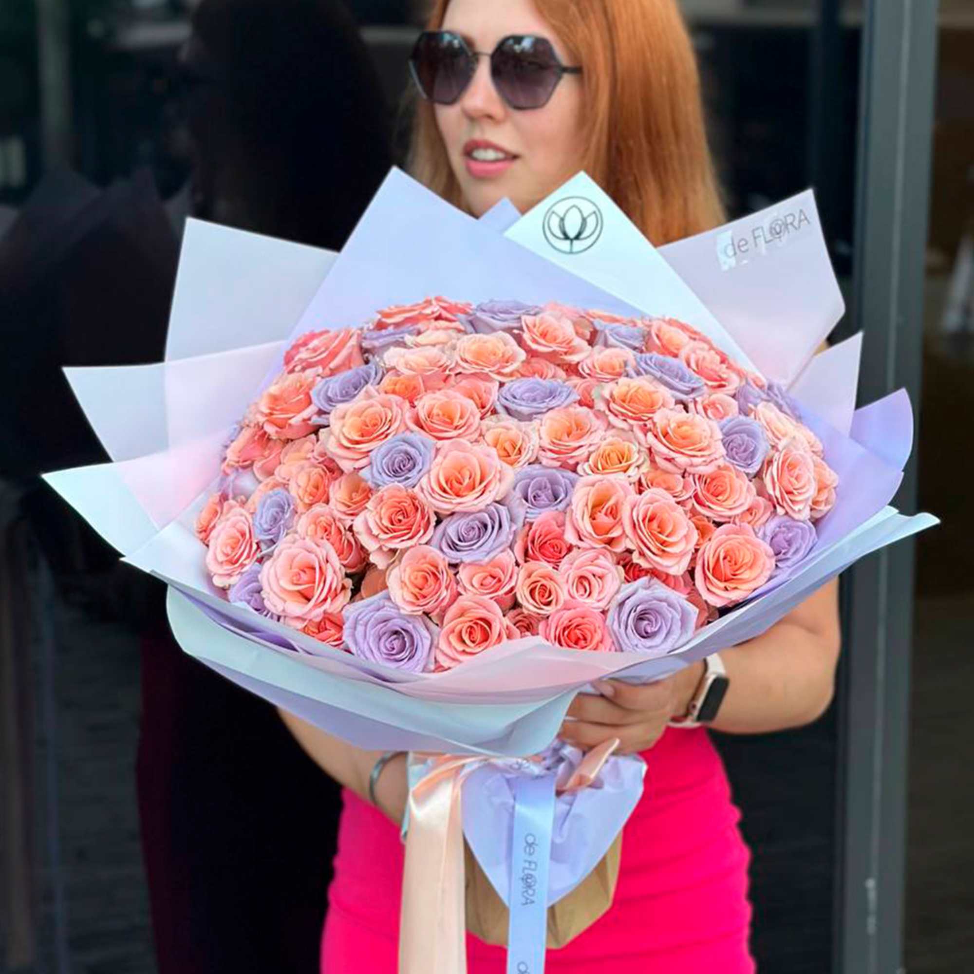 Large bouquet of pink and lavender roses wrapped in pastel paper