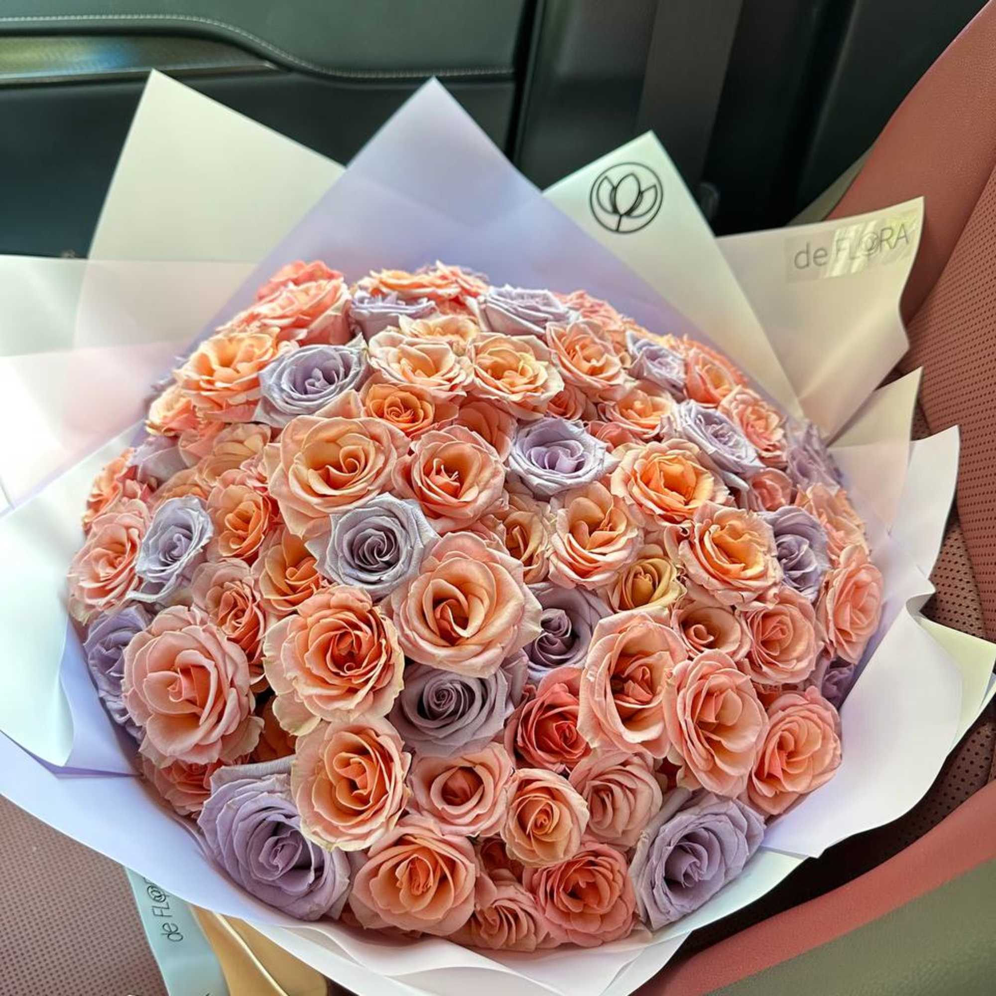 Bouquet of peach and lavender roses wrapped in pastel paper