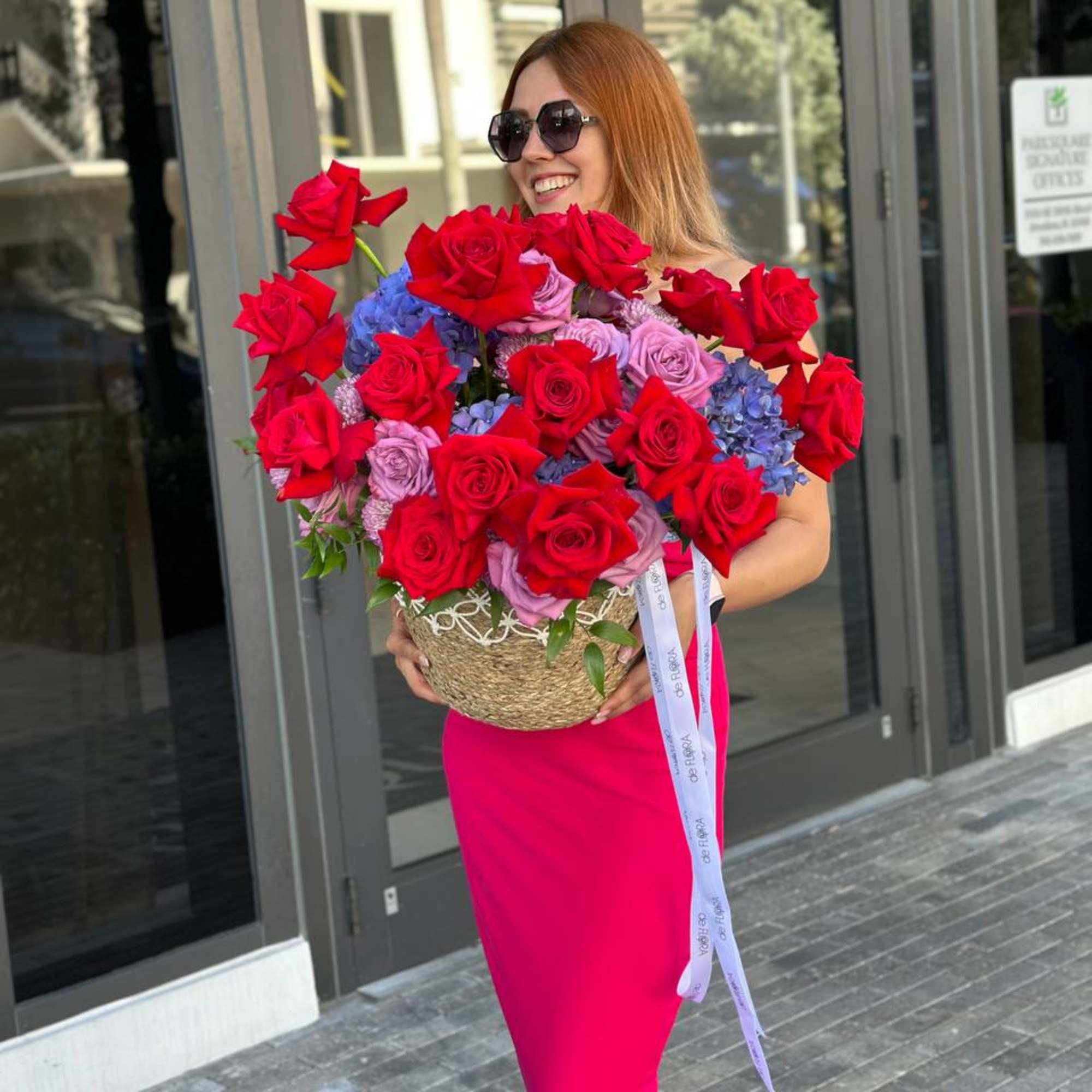 Large bouquet of red and lavender roses with blue hydrangeas in a woven basket