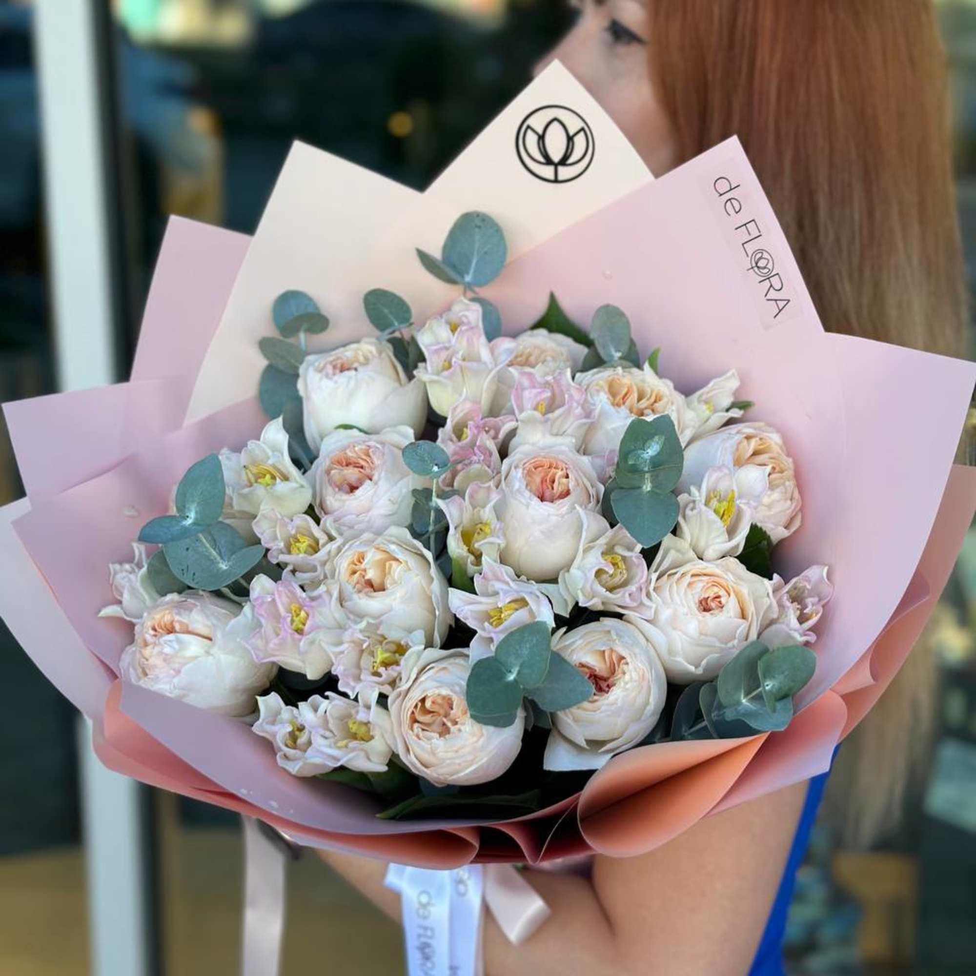 Bouquet of pale pink and white roses wrapped in pink paper