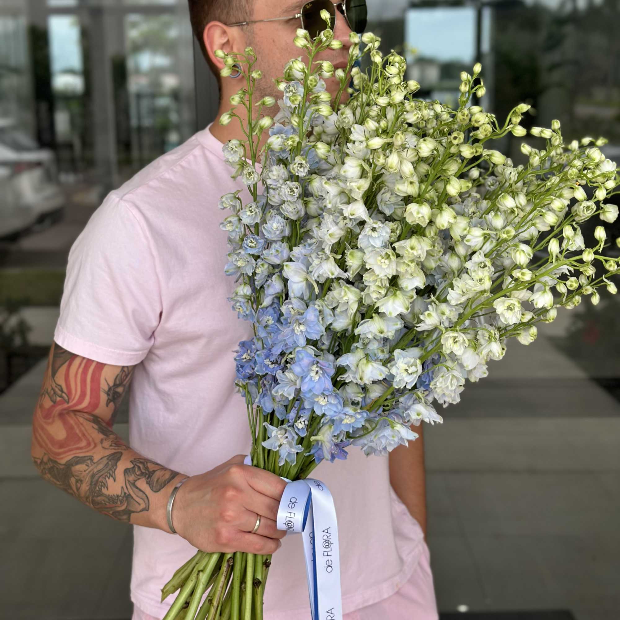 Man holding a large bouquet of pale blue and white flowers