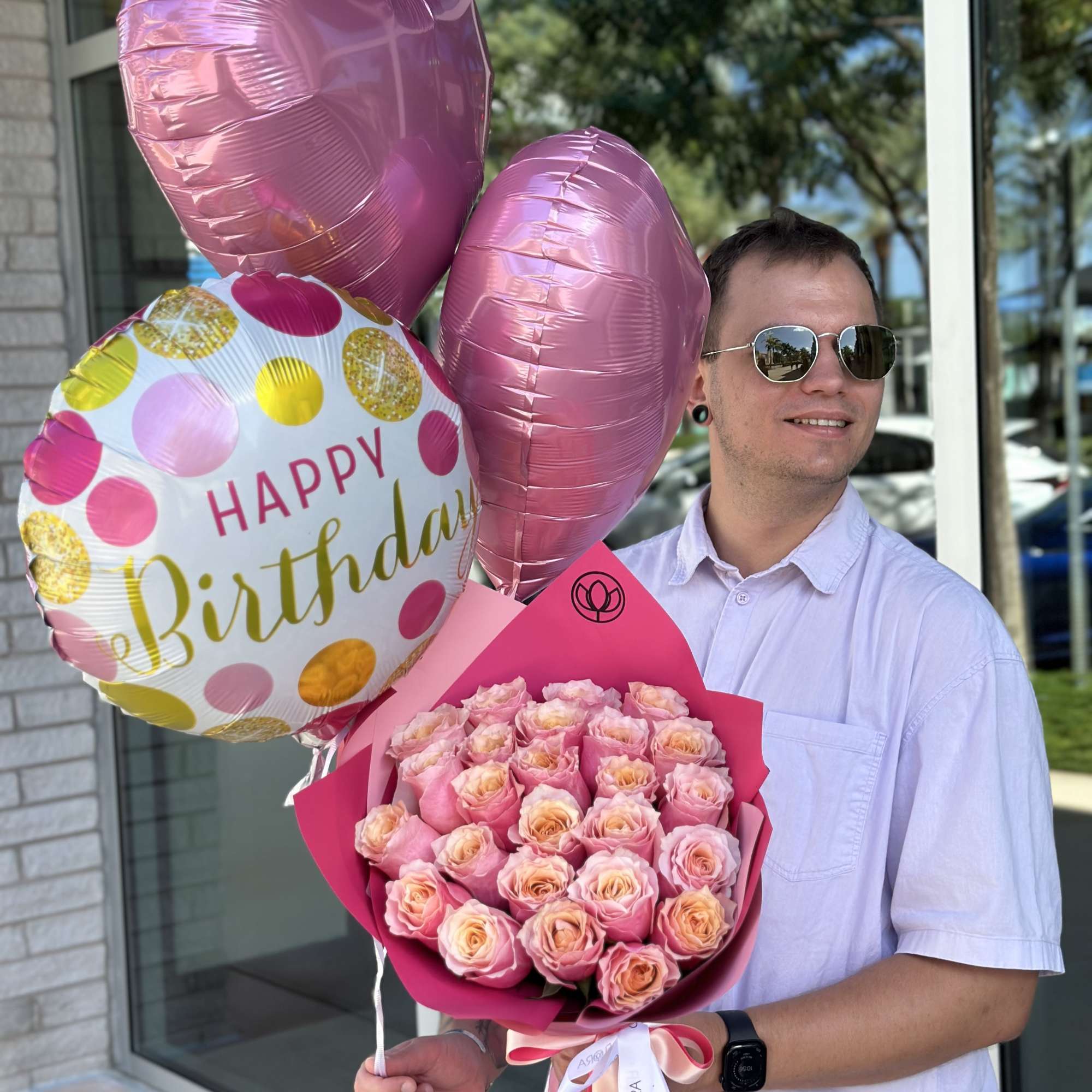 Man holding pink rose bouquet and birthday balloons