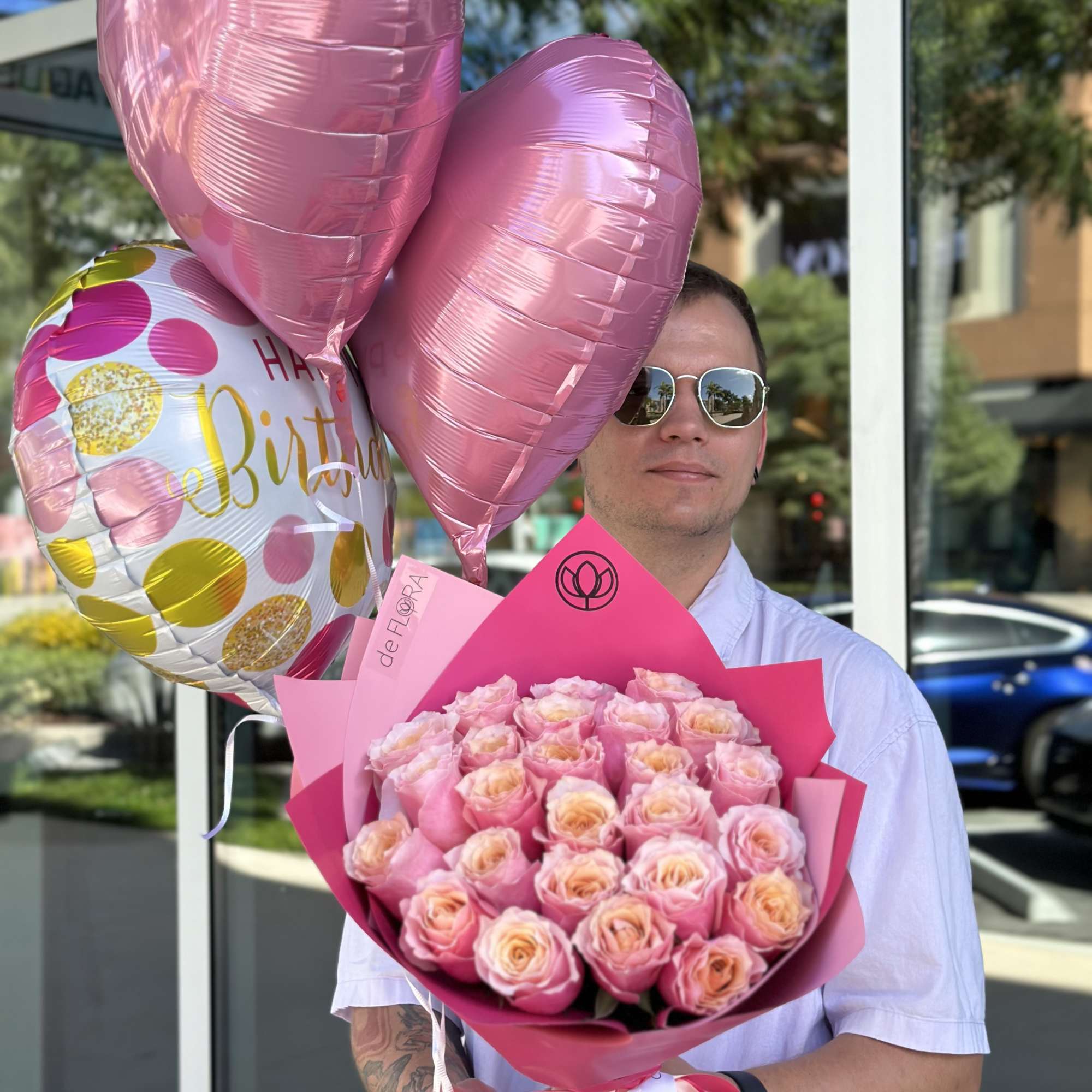 Man holding a pink rose bouquet and heart-shaped balloons