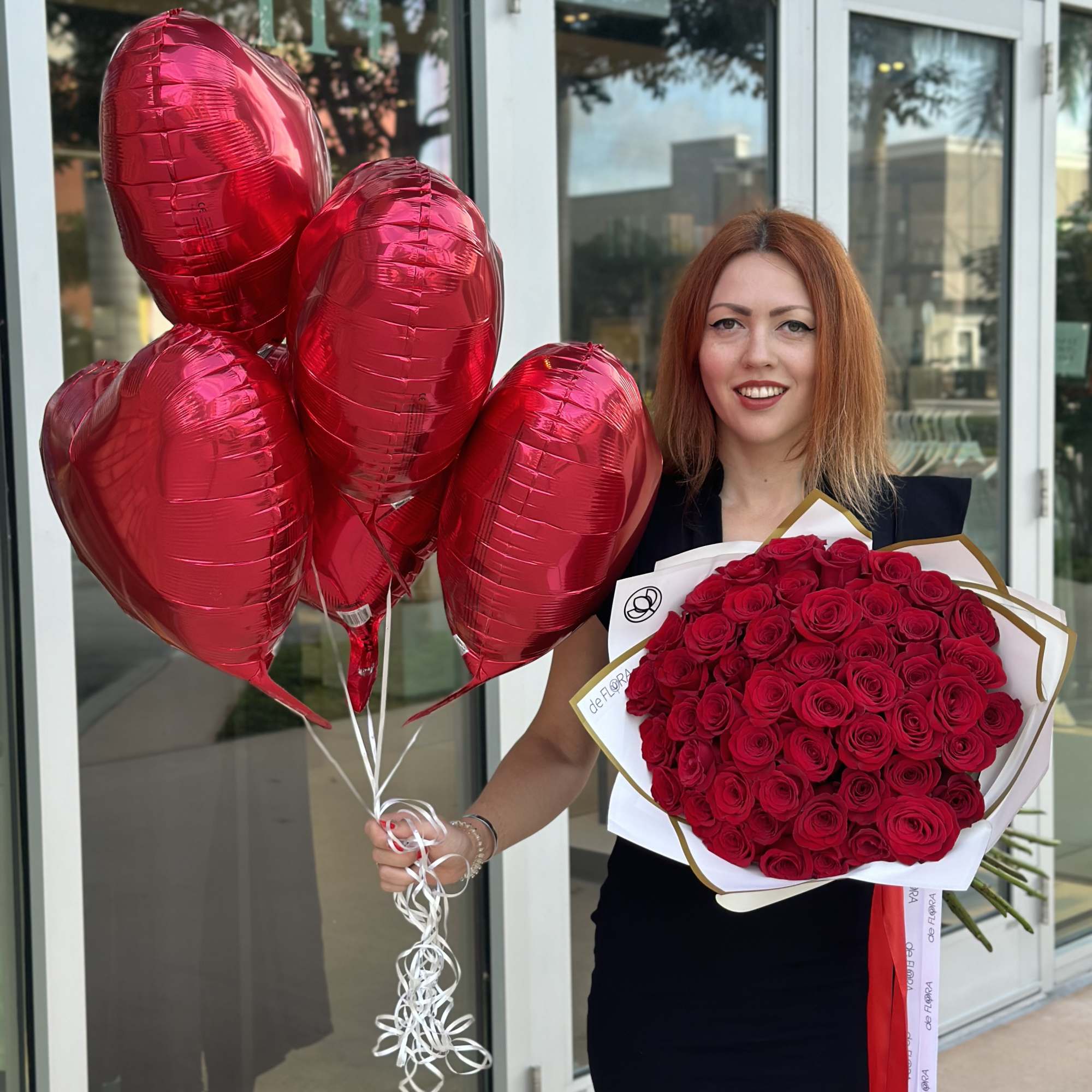 Woman holding red heart balloons and a bouquet of red roses