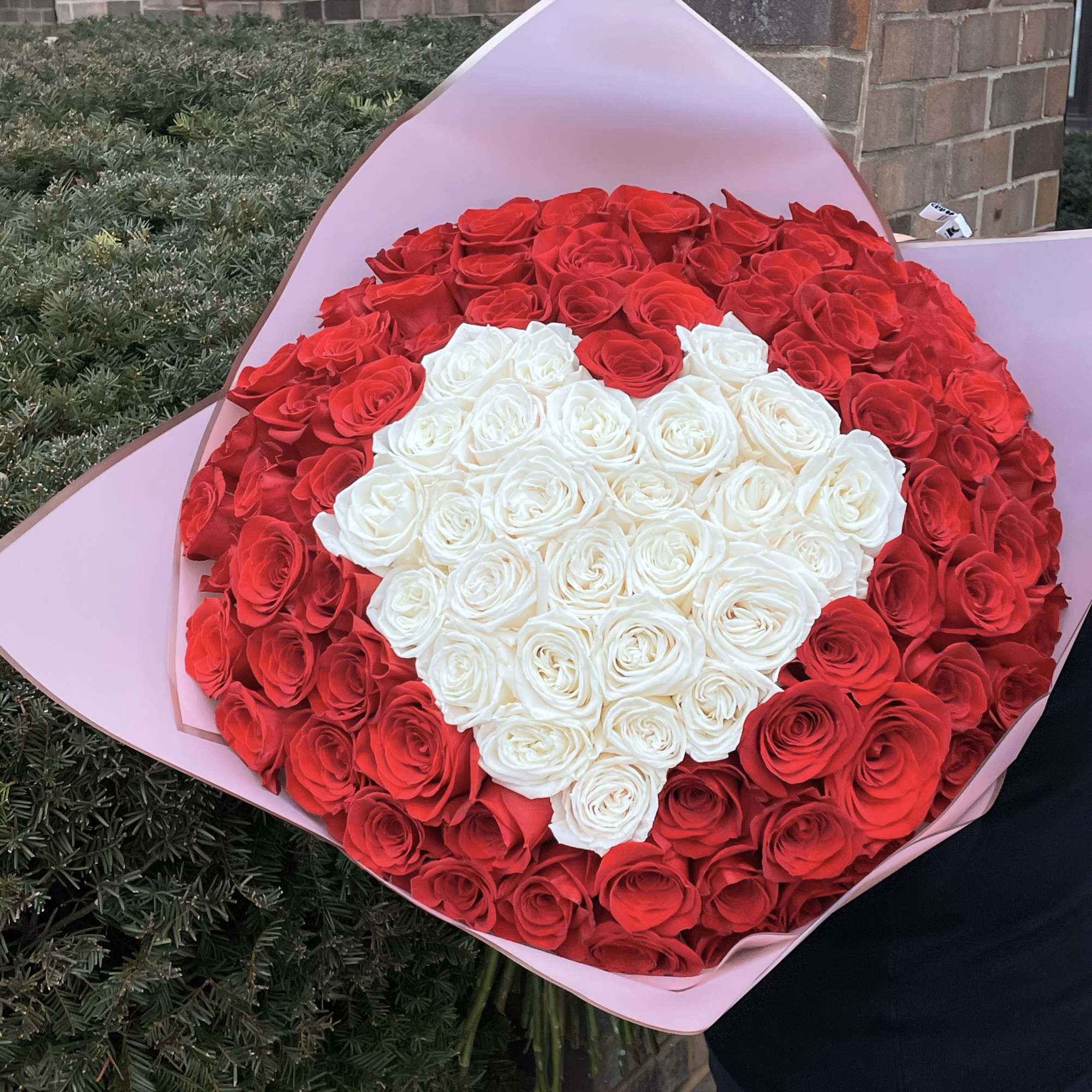 Large bouquet of red and white roses wrapped in pink paper