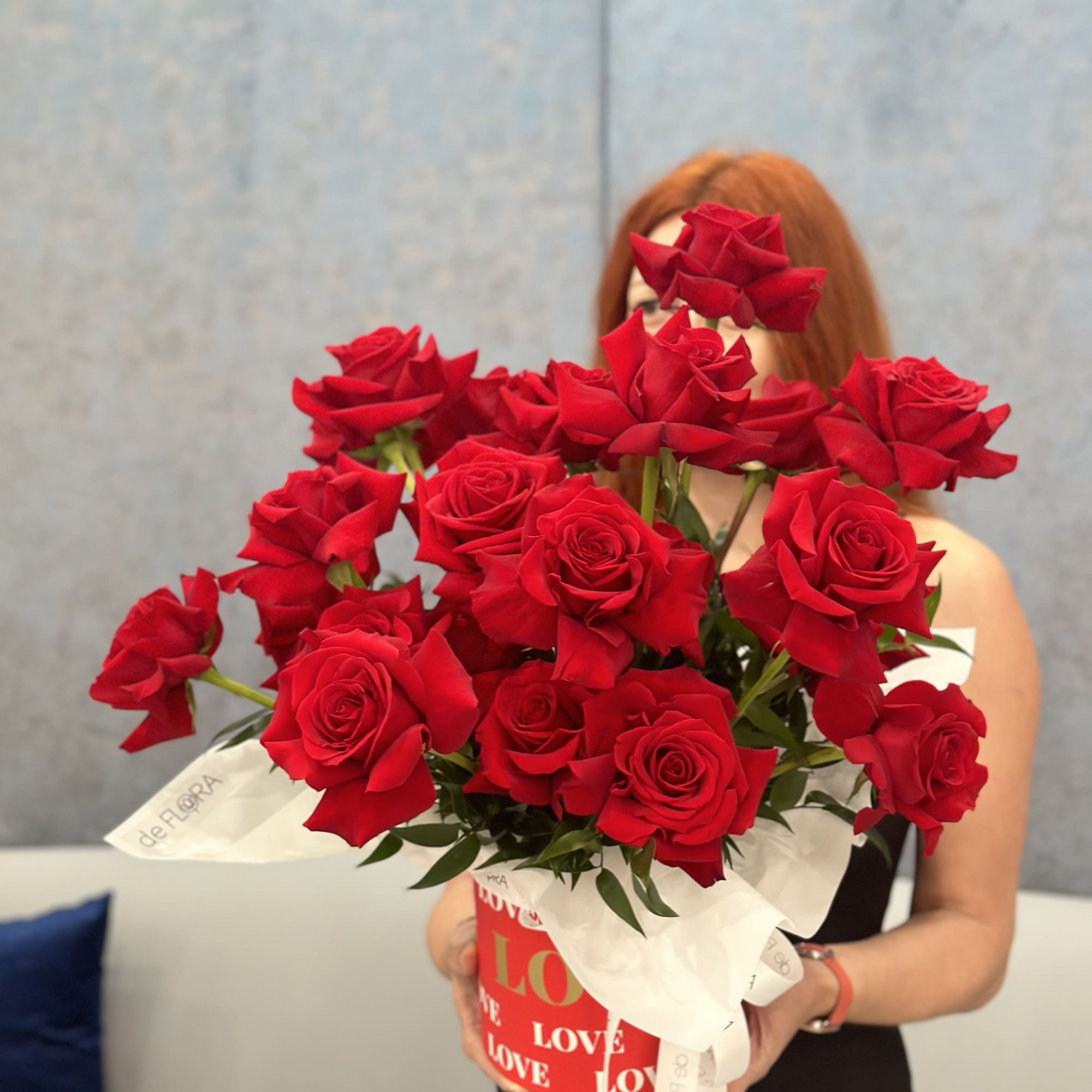 Bouquet of red roses in a red gift box with white ribbon