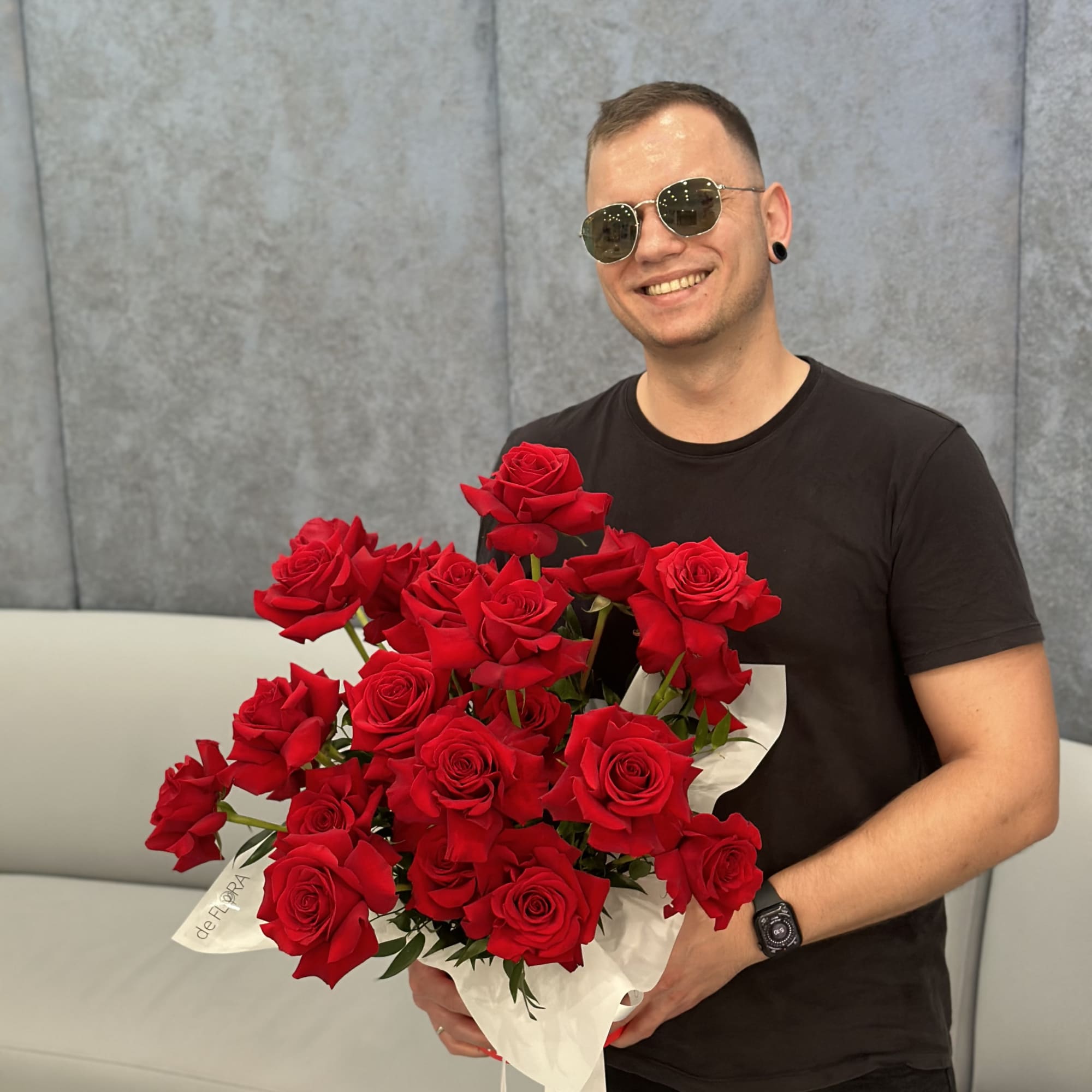 Man holding a large bouquet of red roses wrapped in white paper