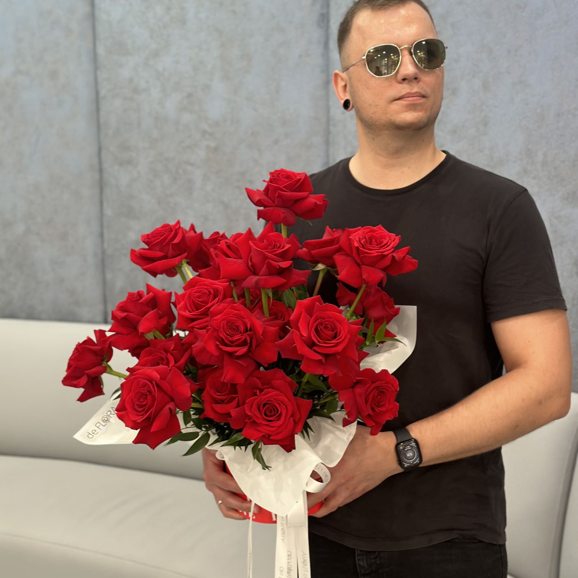 Man holding a large bouquet of red roses wrapped in white paper