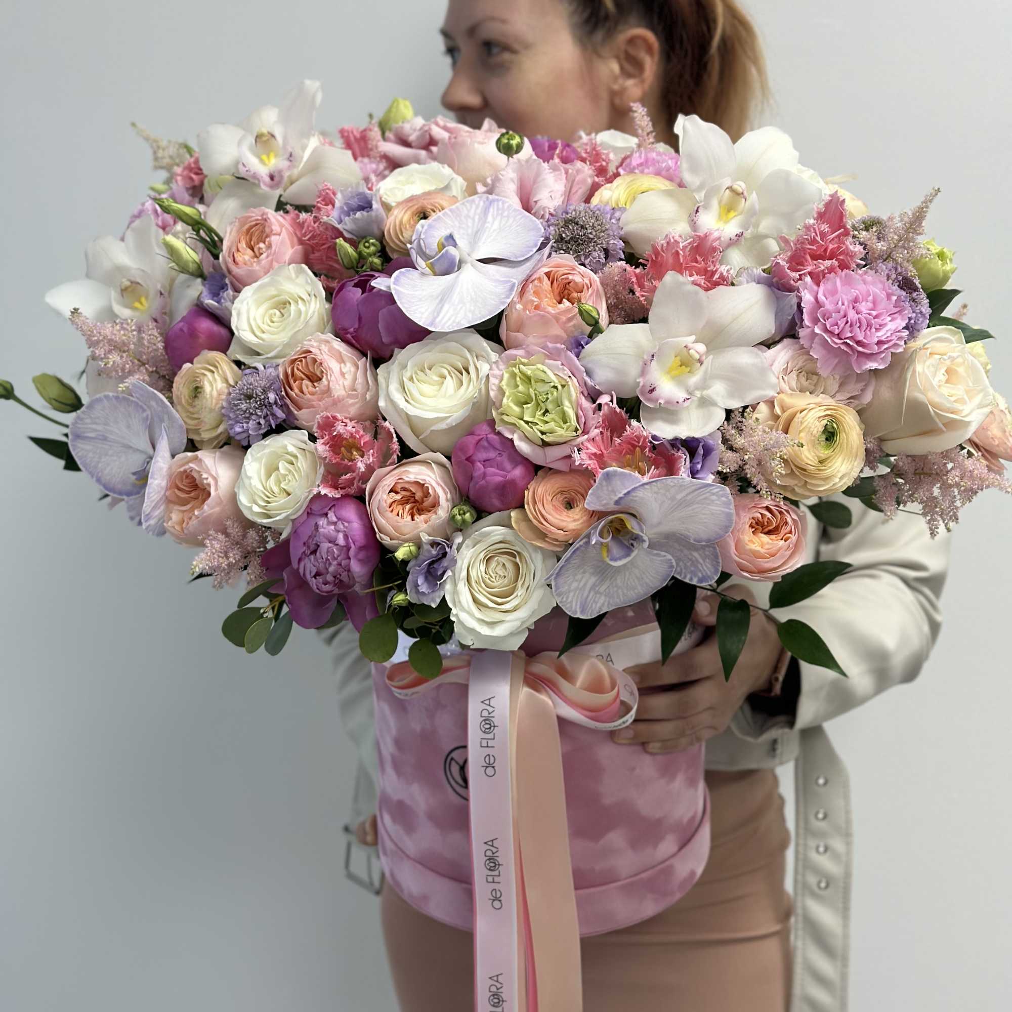 Large pastel bouquet of roses, orchids, and ranunculus in a pink hat box