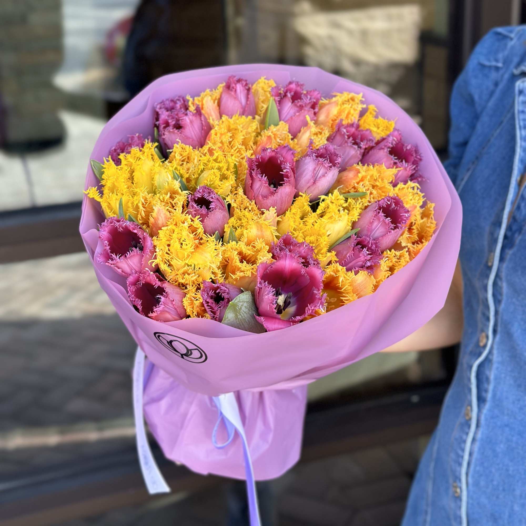 Bouquet of pink and yellow tulips wrapped in lavender paper