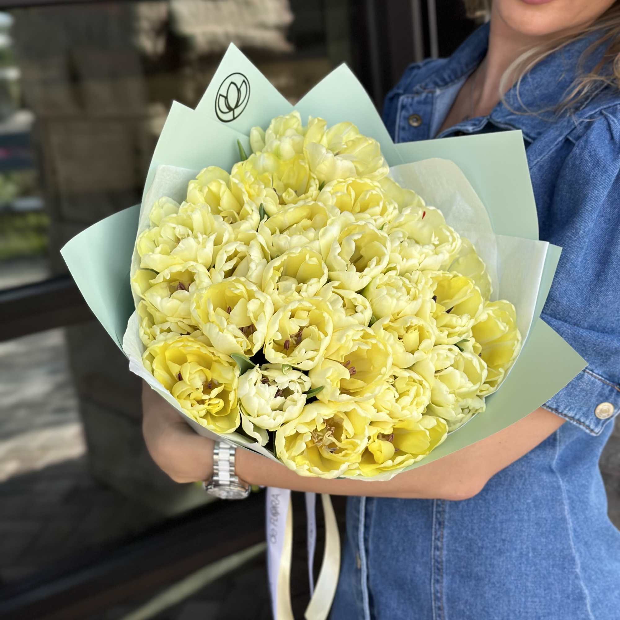 Bouquet of pale yellow tulips wrapped in mint paper