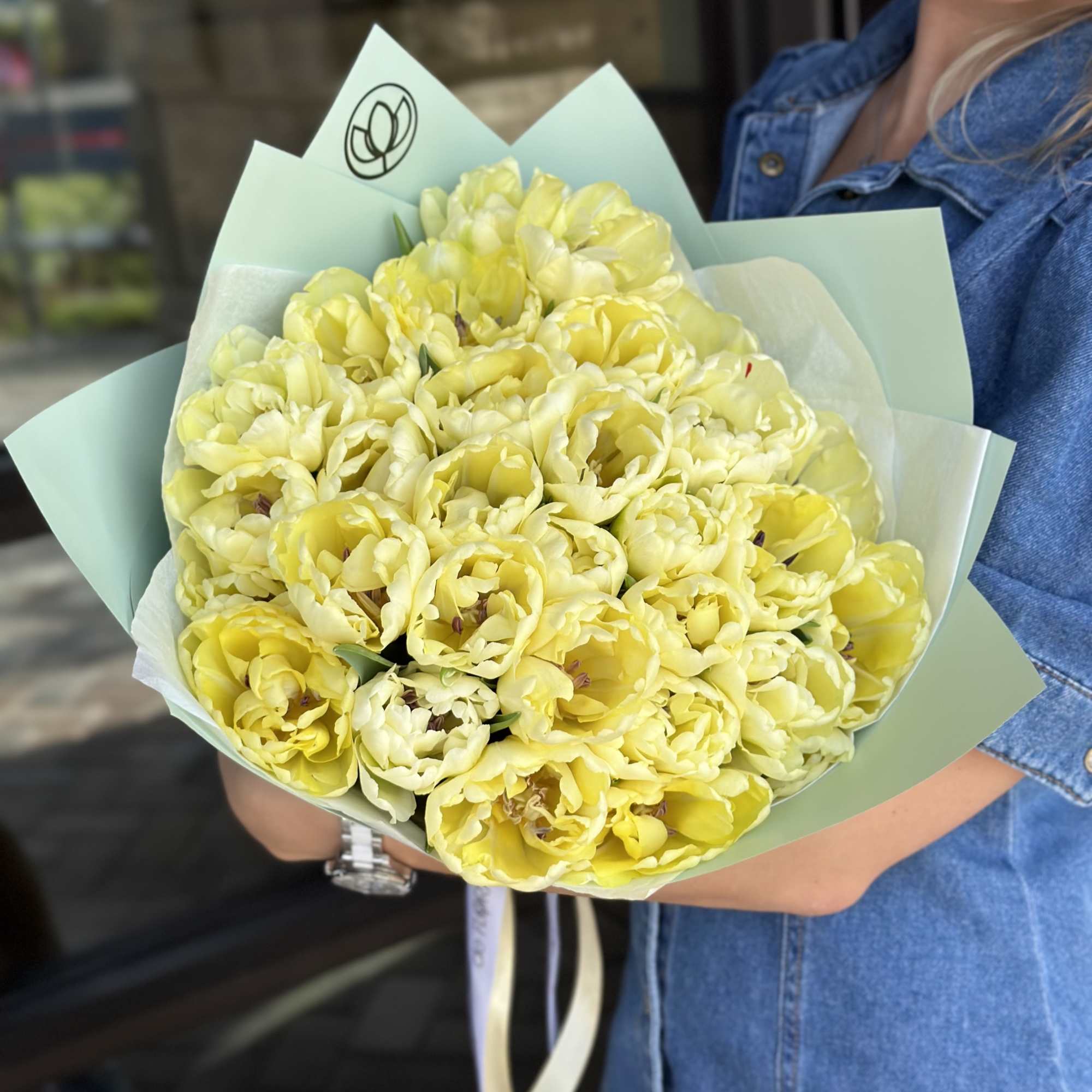 Bouquet of pale yellow tulips wrapped in mint paper