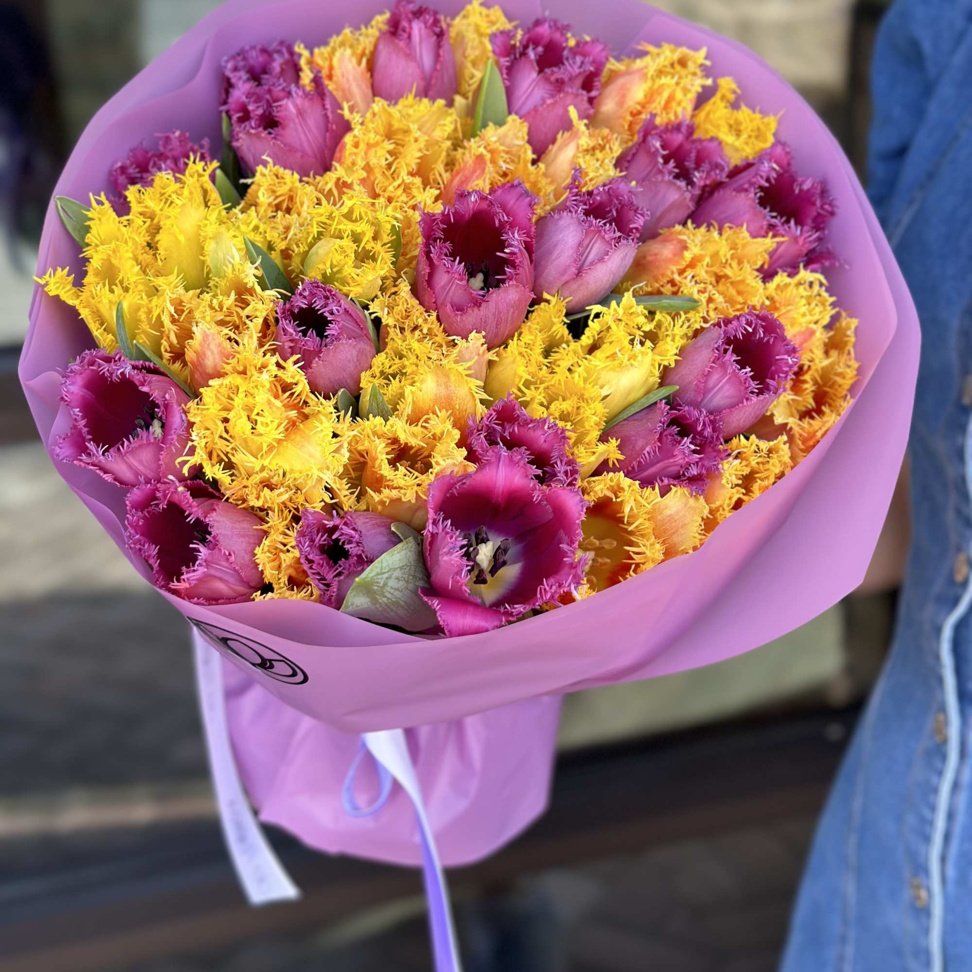Bouquet of purple and yellow tulips wrapped in pink paper