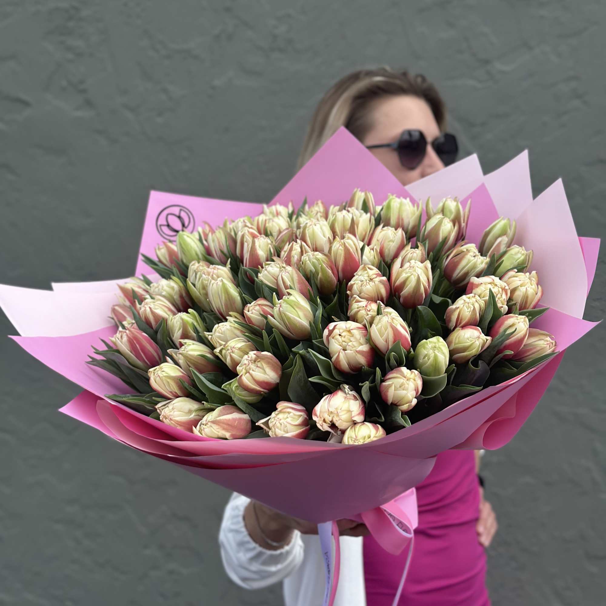 Large bouquet of pale pink and cream tulips wrapped in bright pink paper
