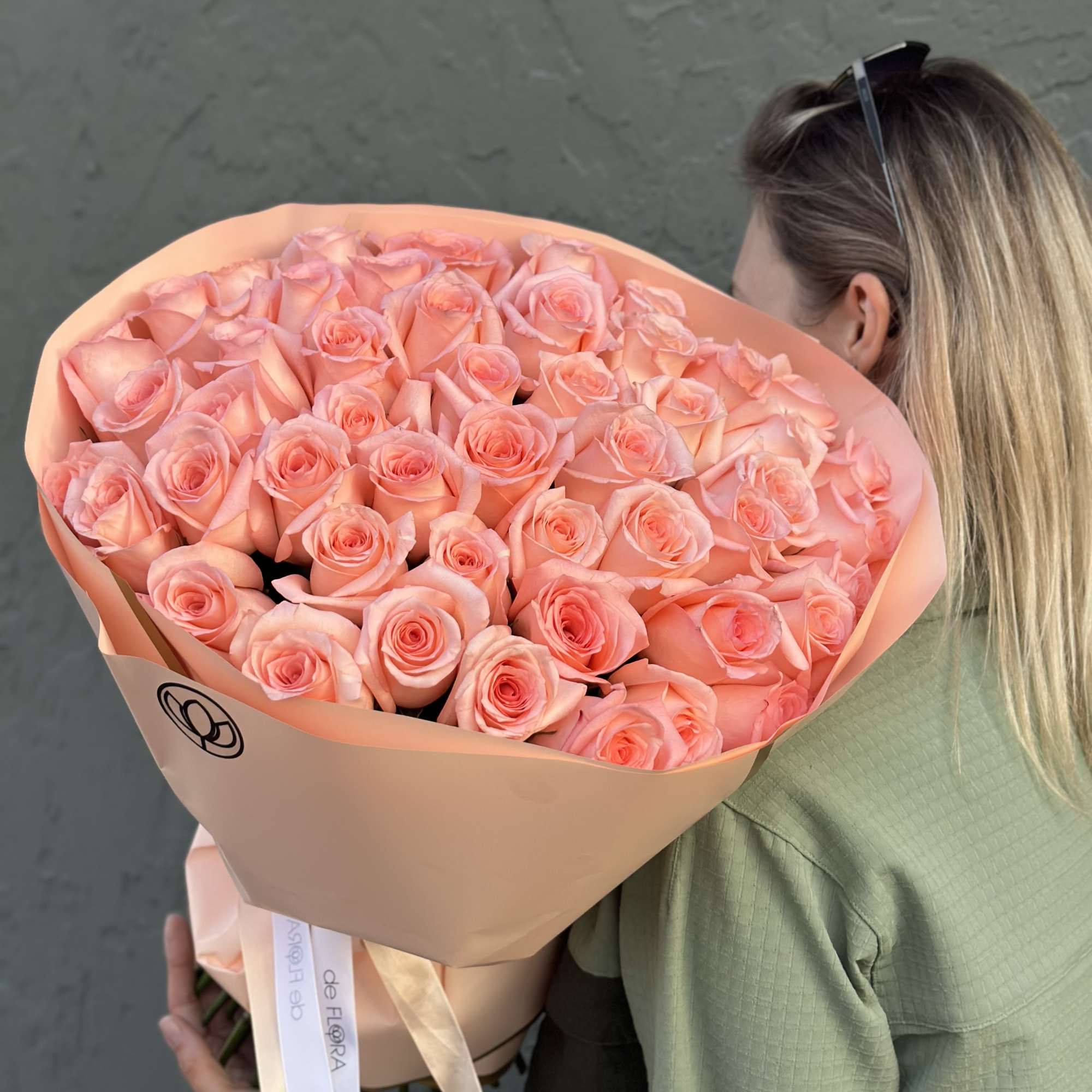 Large bouquet of peach-pink roses wrapped in tan paper