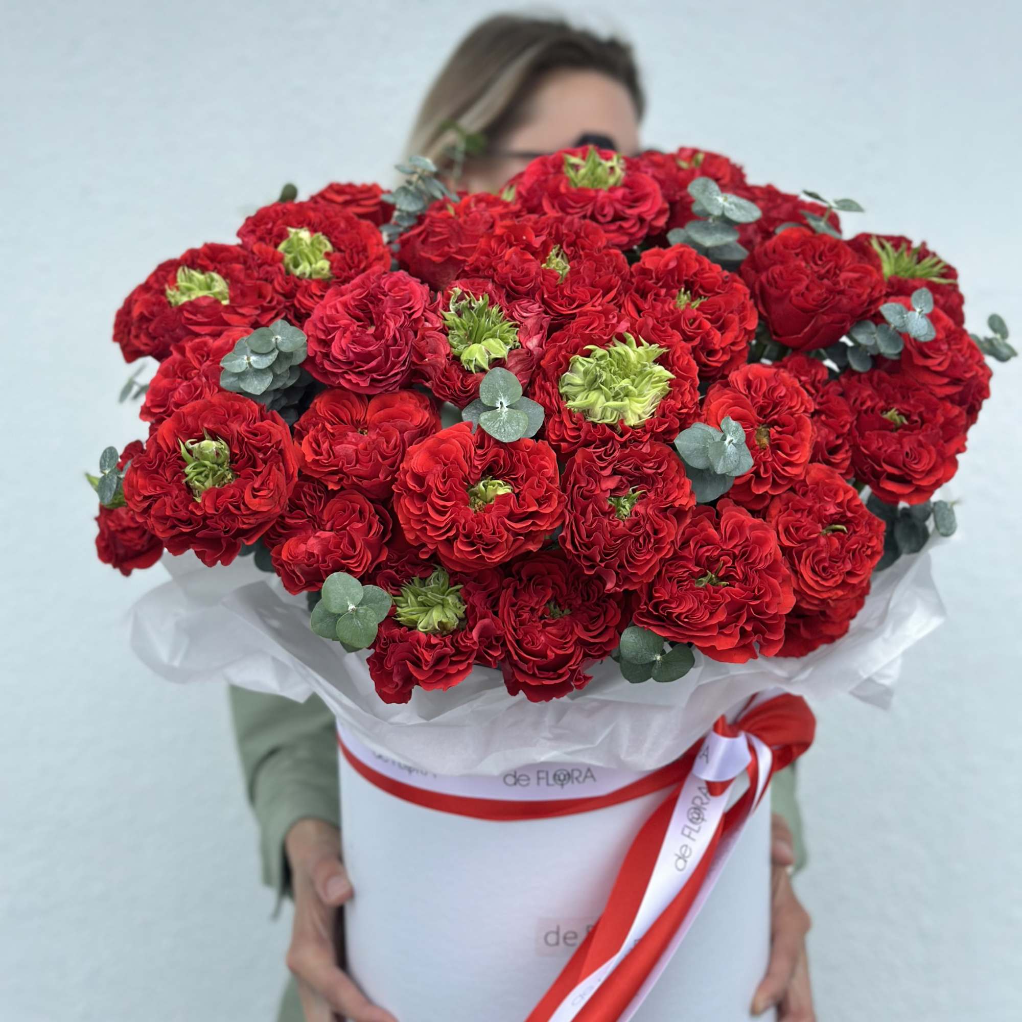 Large bouquet of red carnations in a white hatbox with a red ribbon