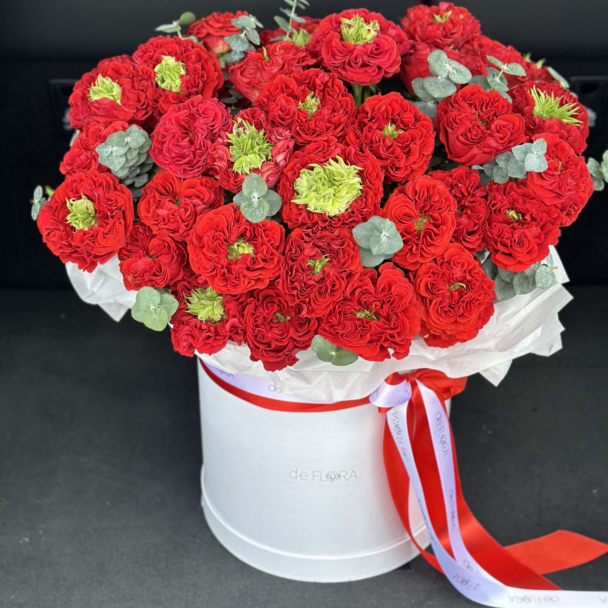 Bouquet of red roses in a white hatbox with a red ribbon