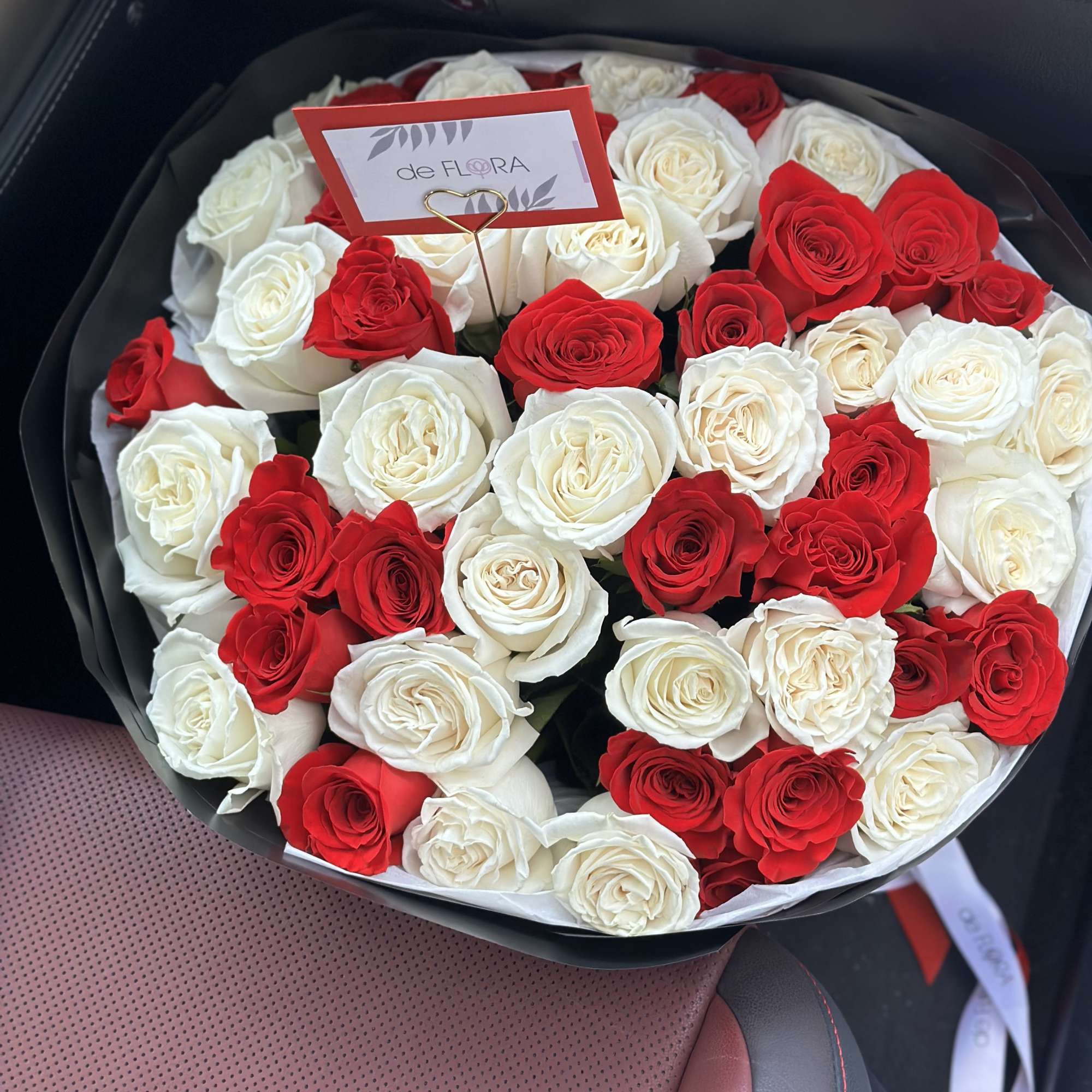 Round bouquet of red and white roses in black wrapping