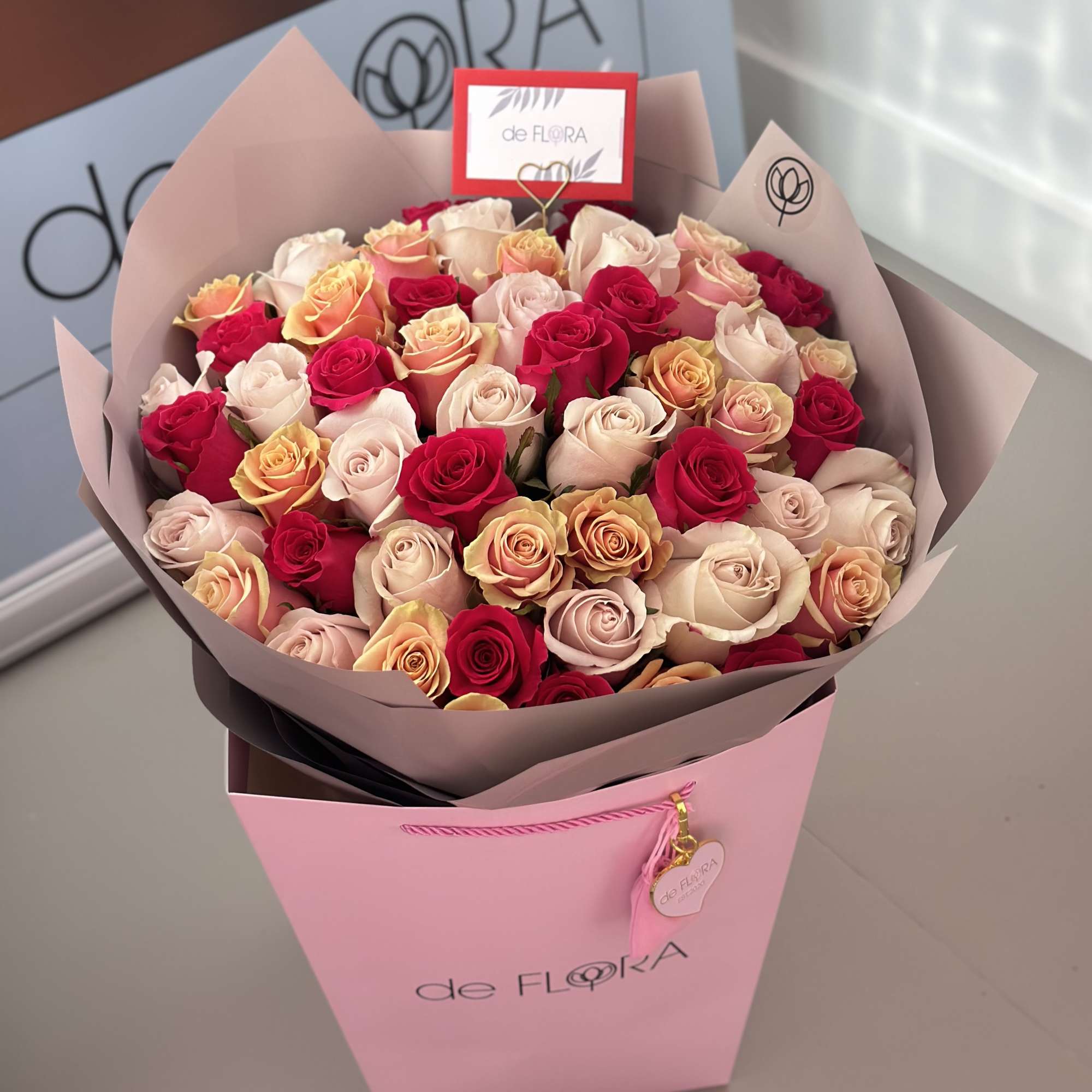 Bouquet of pink, cream, and red roses in a pink gift box