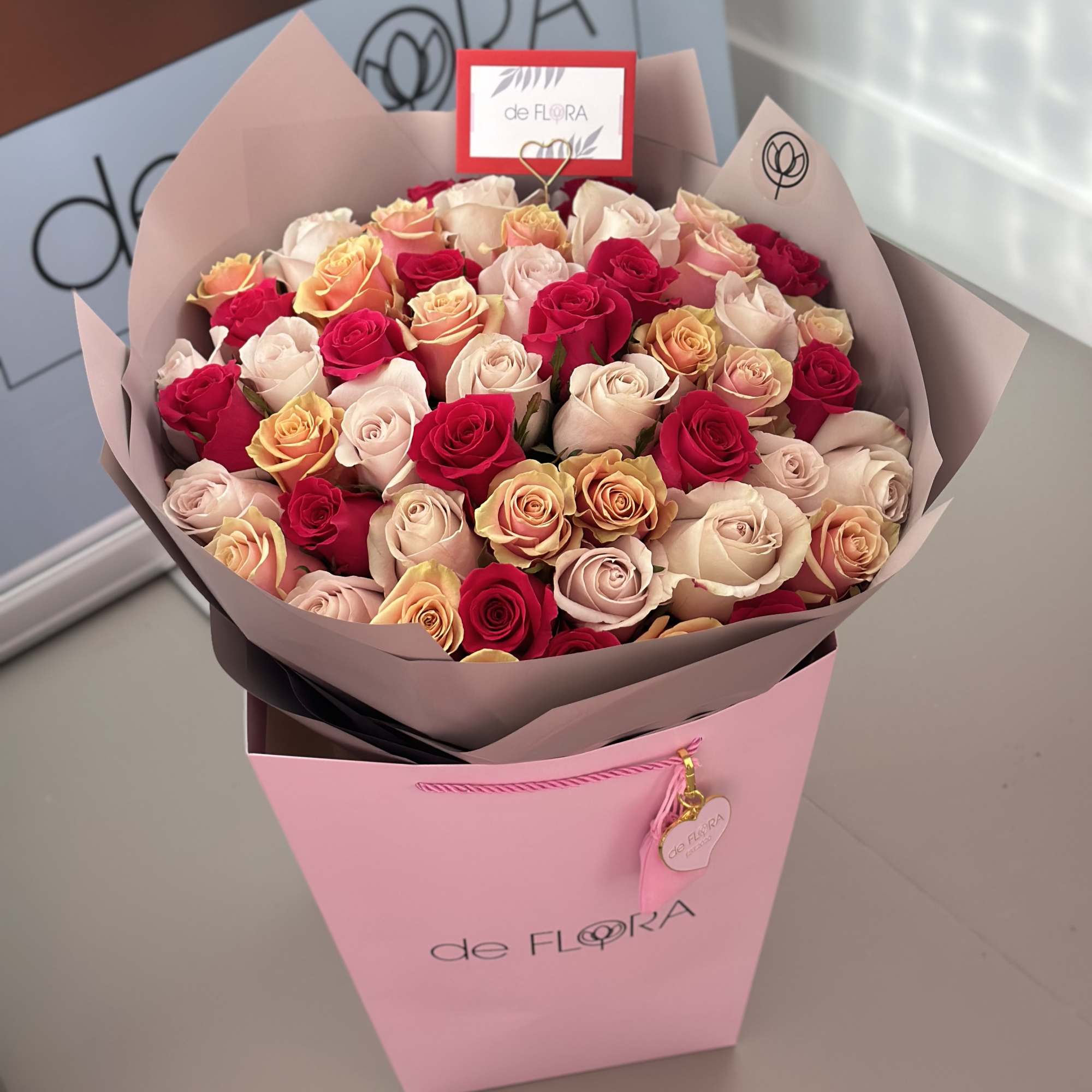 Bouquet of pink, cream, and red roses in a pink gift box