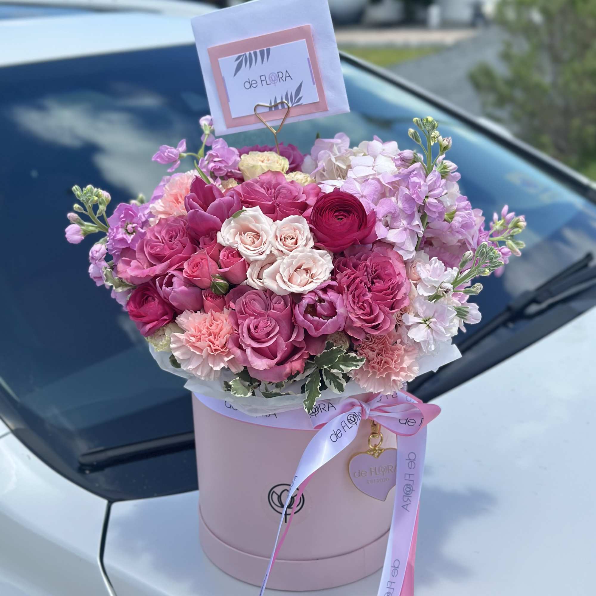 Pink rose bouquet in a round box with a ribbon and card