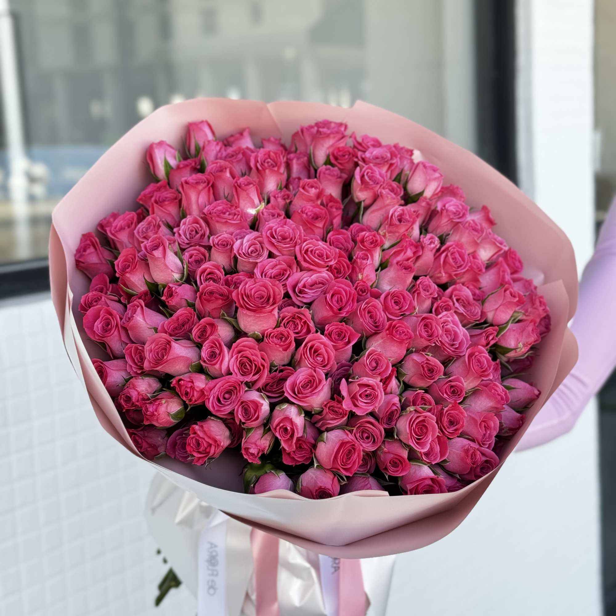 Large bouquet of bright pink roses wrapped in pale pink paper