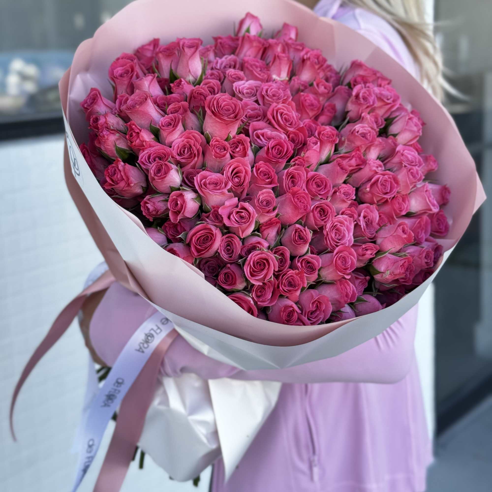 Large bouquet of bright pink roses wrapped in pale pink paper