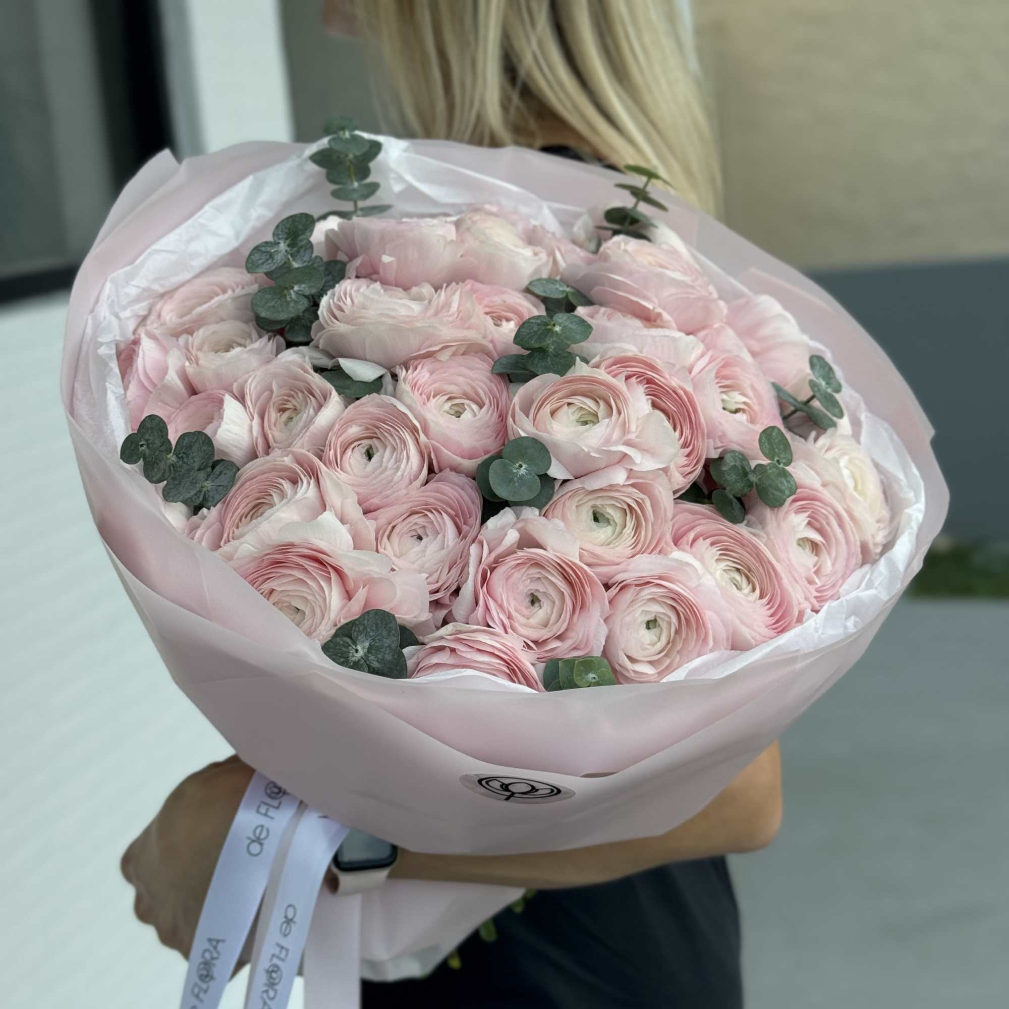 Bouquet of pale pink ranunculus with eucalyptus in pink wrapping