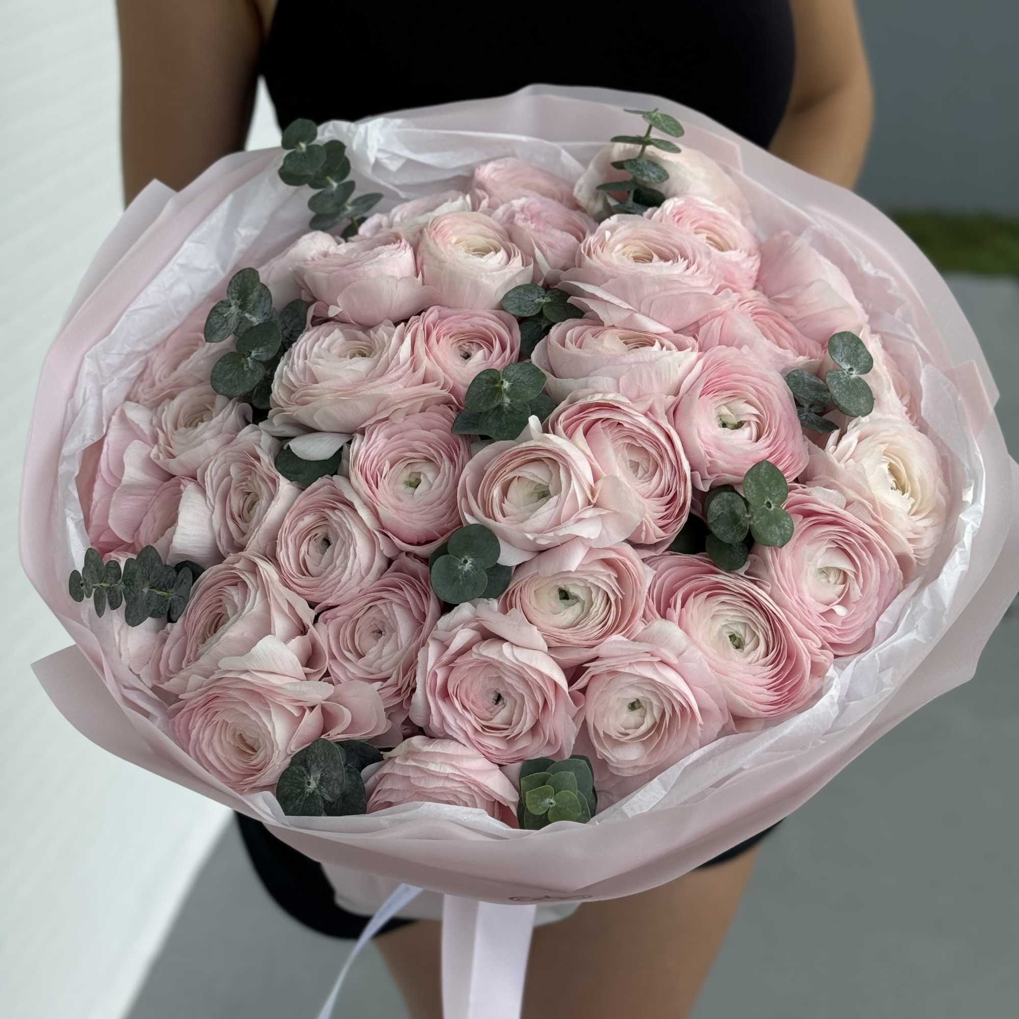 Bouquet of pale pink ranunculus with eucalyptus in pink wrap