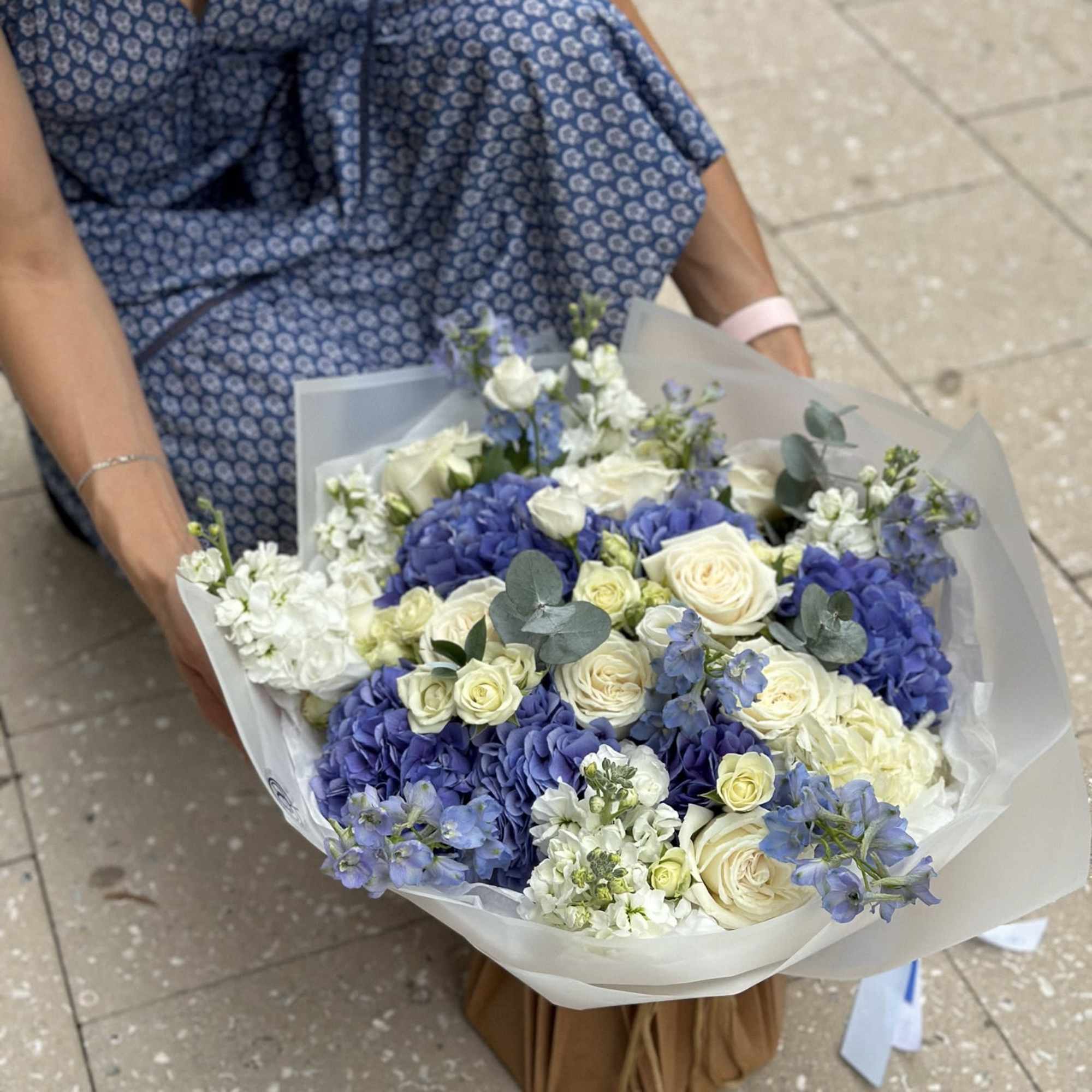 Large bouquet of blue and white flowers wrapped in translucent paper