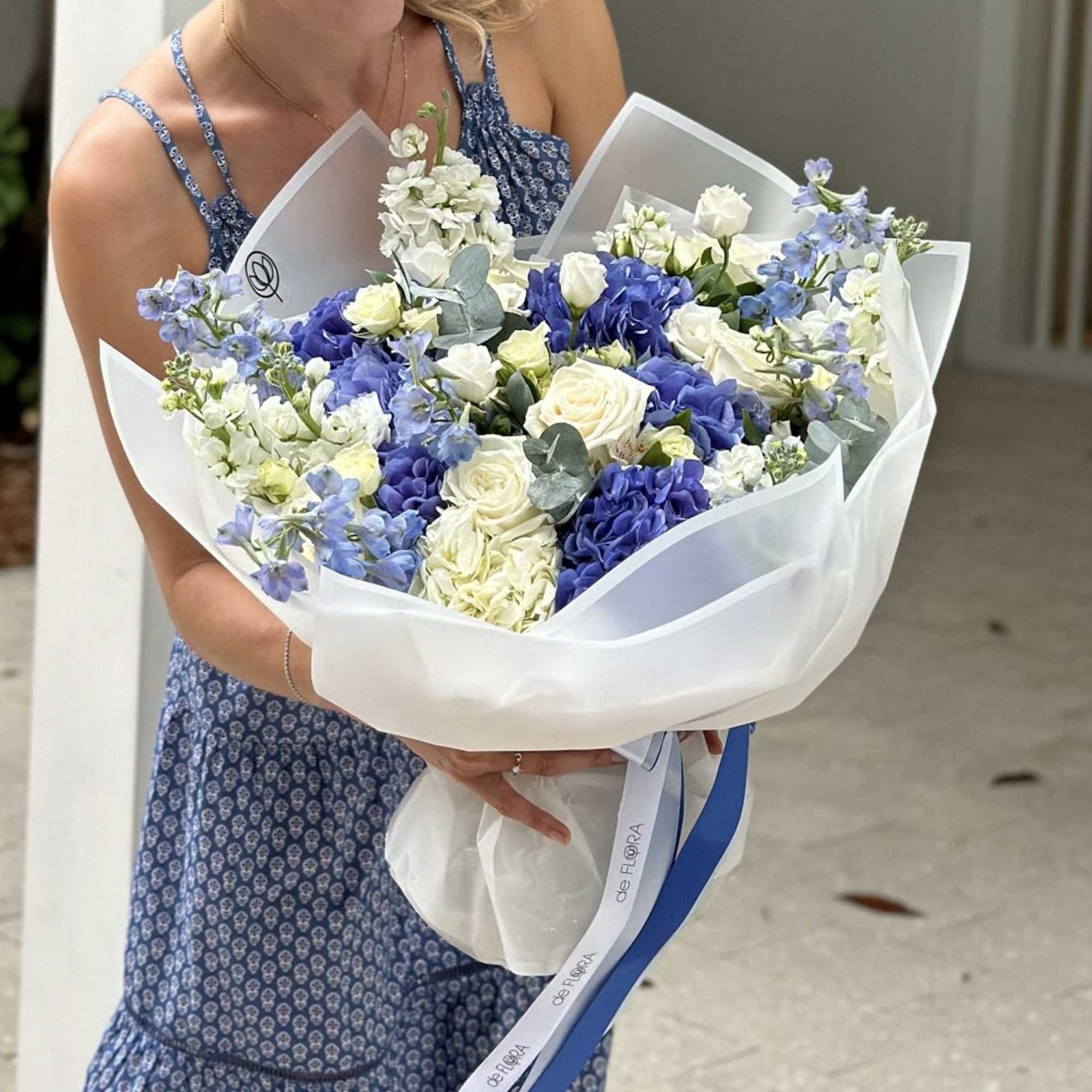 Bouquet of blue and white flowers wrapped in white paper