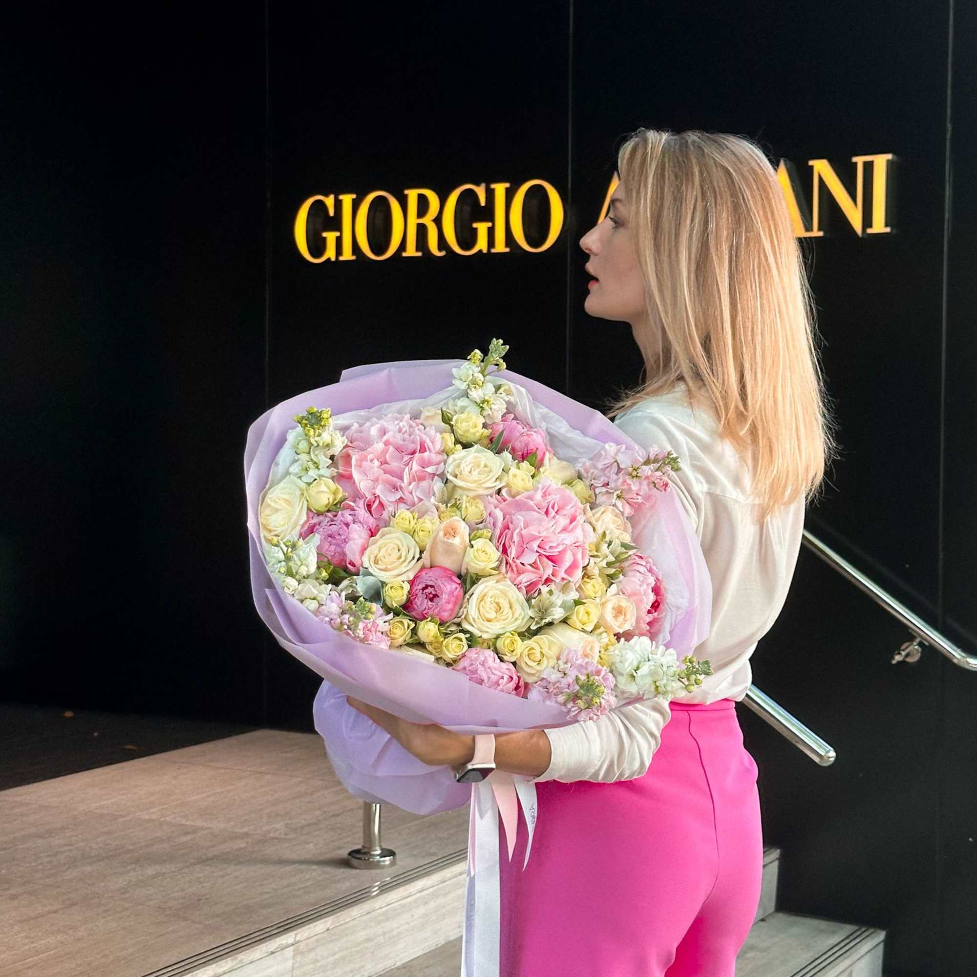 Woman holding a large pastel bouquet of pink and cream flowers