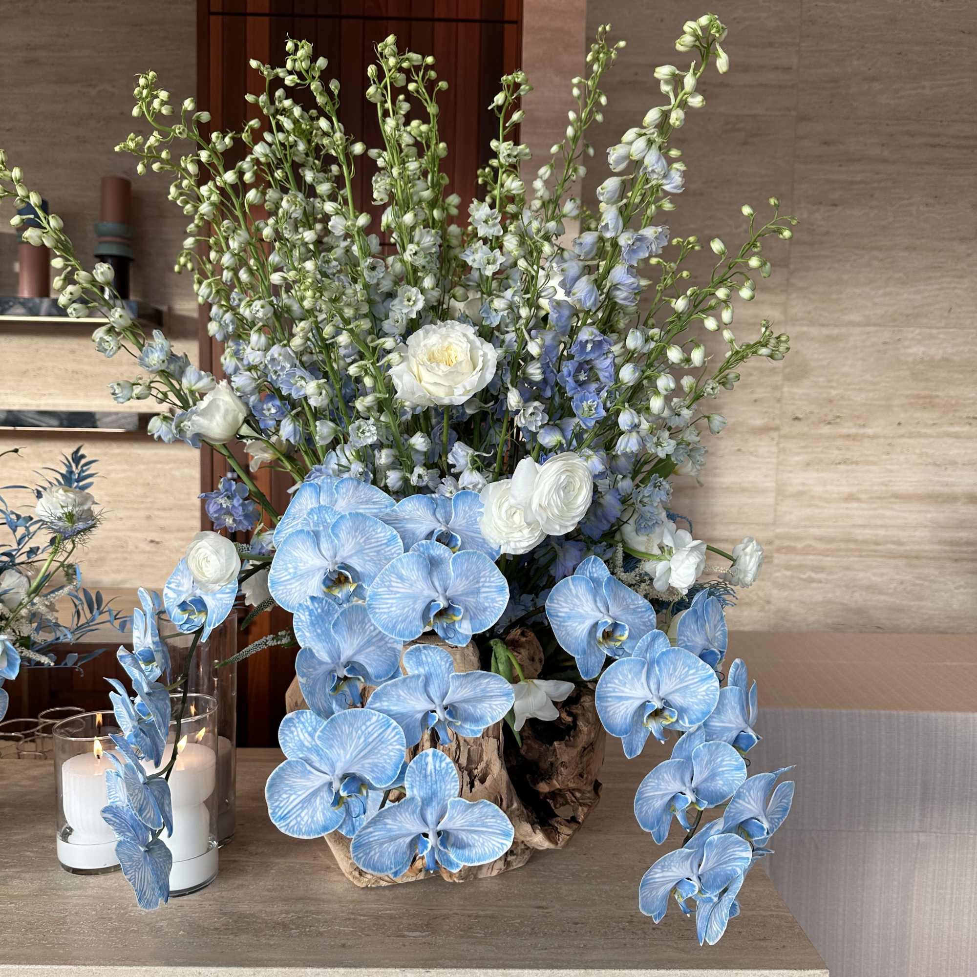 Tall blue and white floral arrangement in a rustic wood container