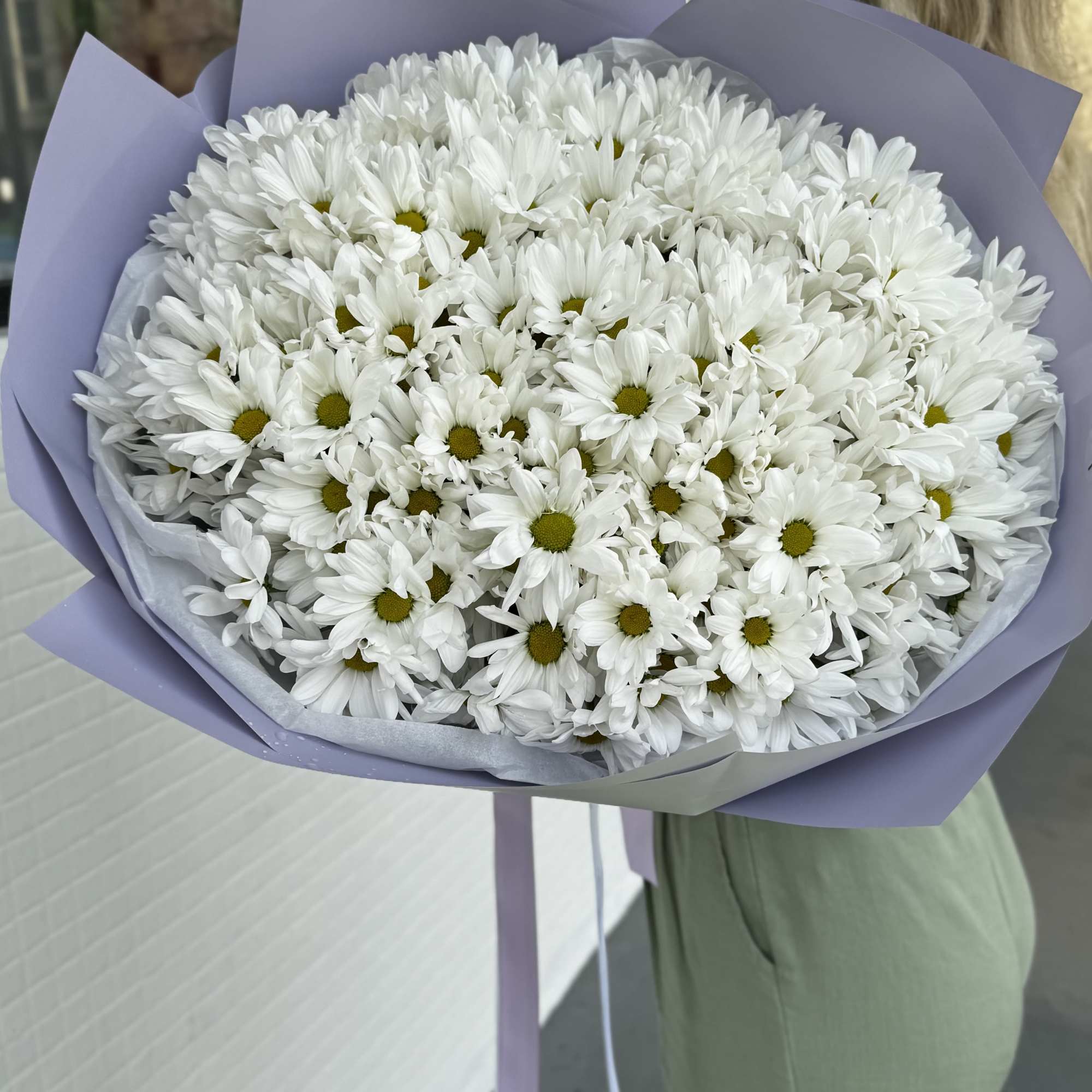 Large bouquet of white daisies wrapped in lavender paper